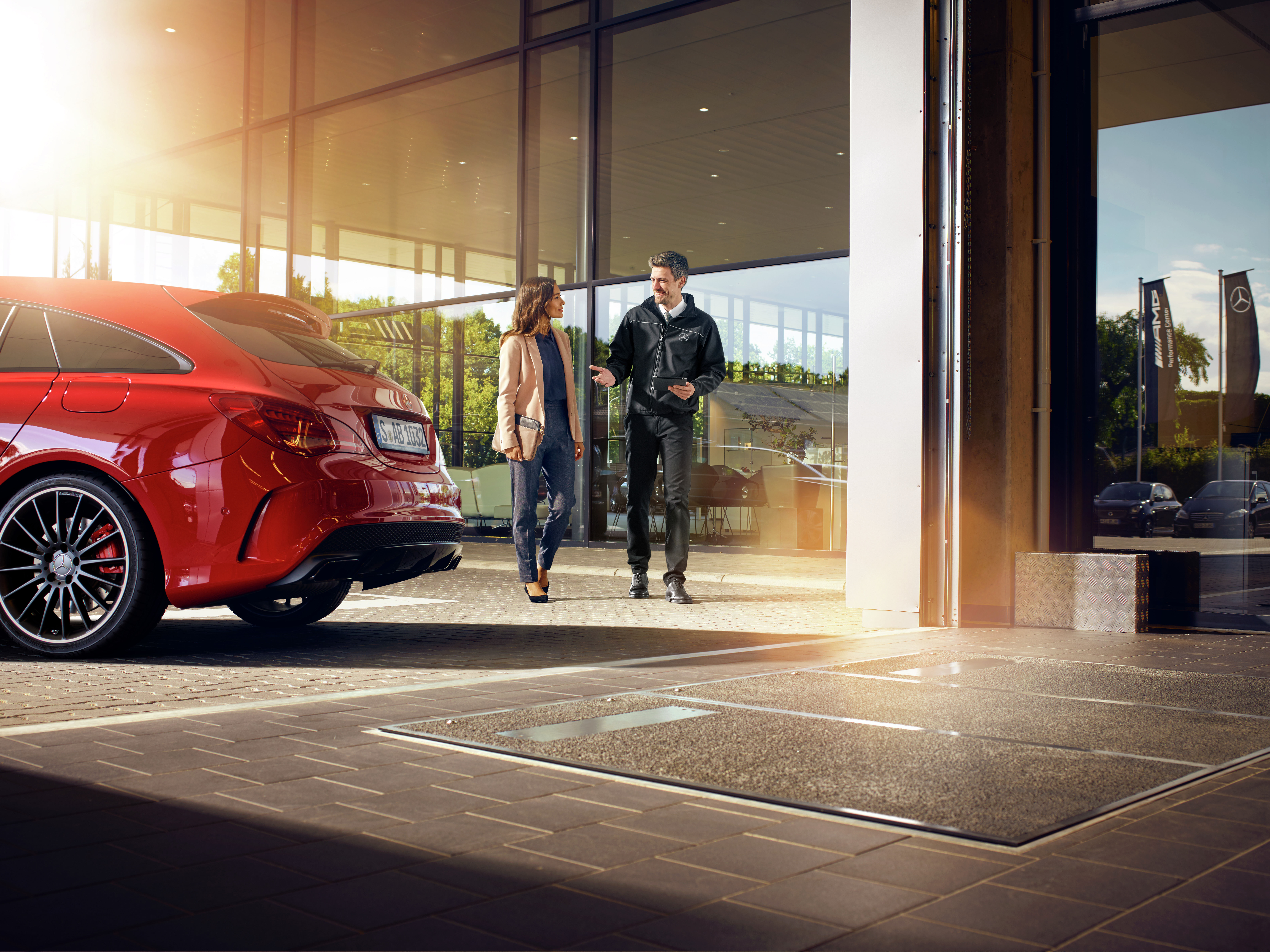 Couple leaving a showroom beside a red car Couple leaving a showroom beside a red car.