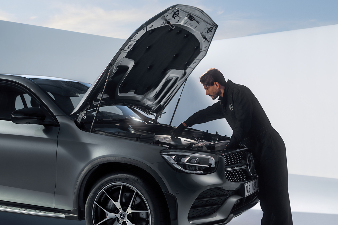 Technician checking an engine under an open bonnet Technician checking an engine under an open bonnet
