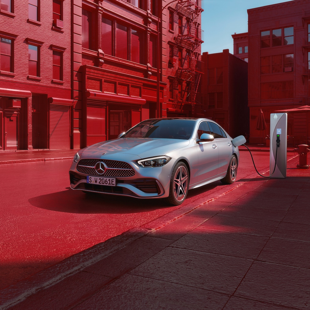 Dynamic view of a Mercedes-Benz C-Class Saloon (driving shot) or standing at a charging station.