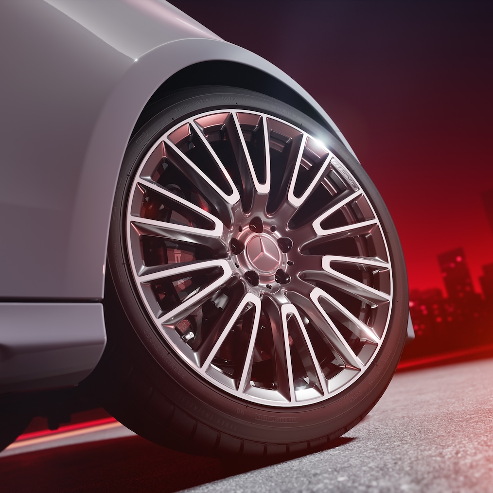 Close-up of AMG forged wheel (RWB) with brake calliper painted in silver, view from below against a red background.