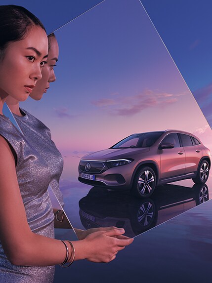 Woman holding rectangular mirror with Mercedes car in reflection