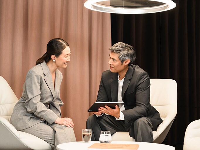 Two people sat in a showroom, looking at information on a tablet device.