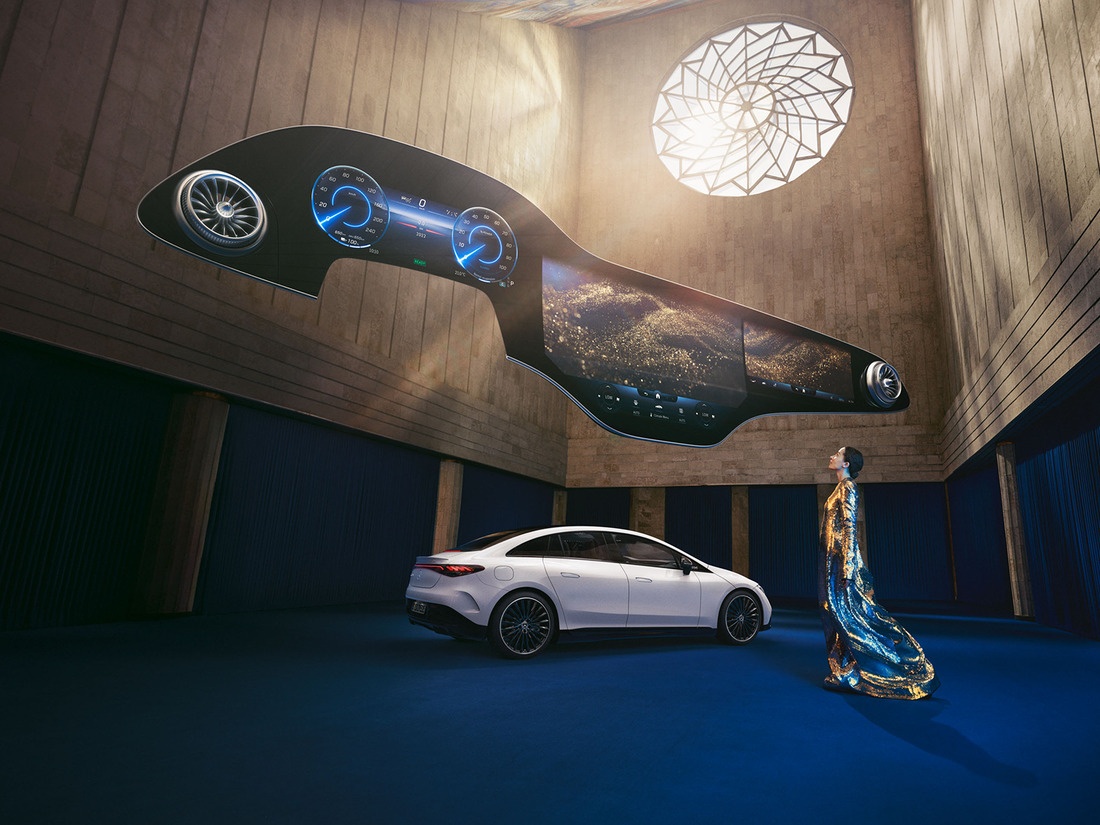 Woman standing in front of Mercedes-Benz EQ vehicle with the Hyperscreen hovering above her. Mercedes-Benz Hyperscreen