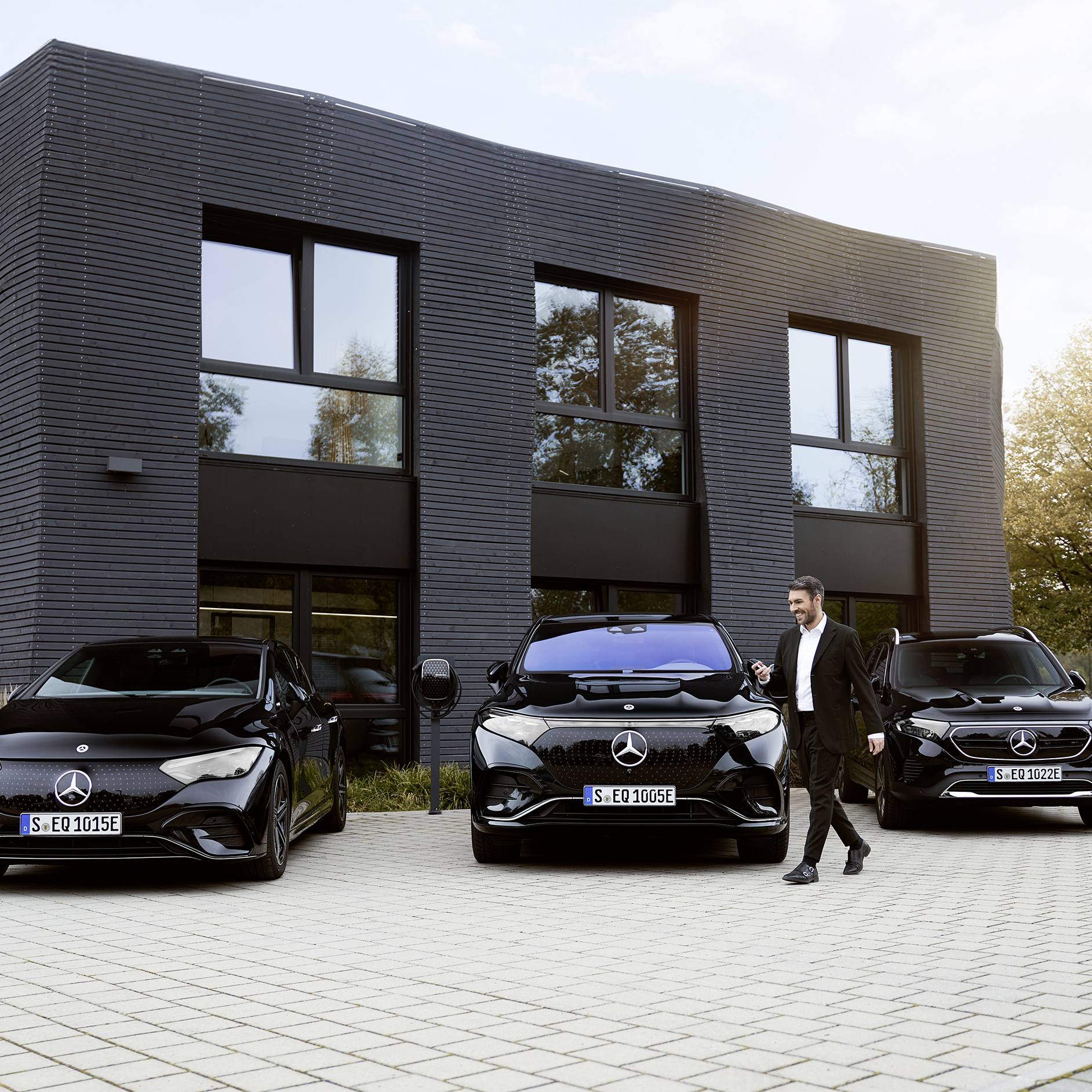 Depot charging | Charging | Mercedes-Benz Three electric Mercedes-Benz cars in front of an office building.
