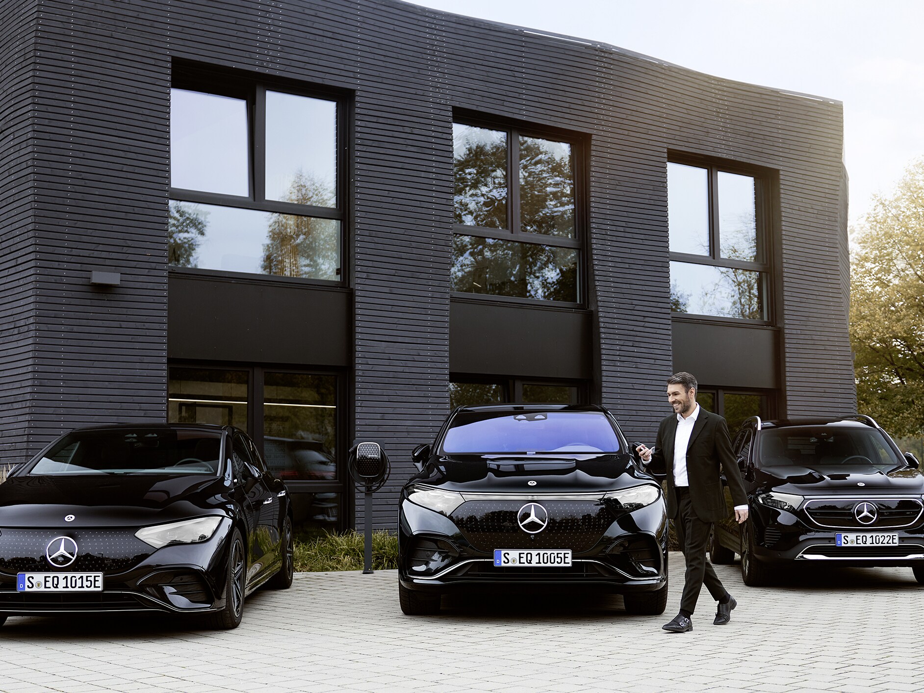 Three electric Mercedes-Benz cars in front of an office building.