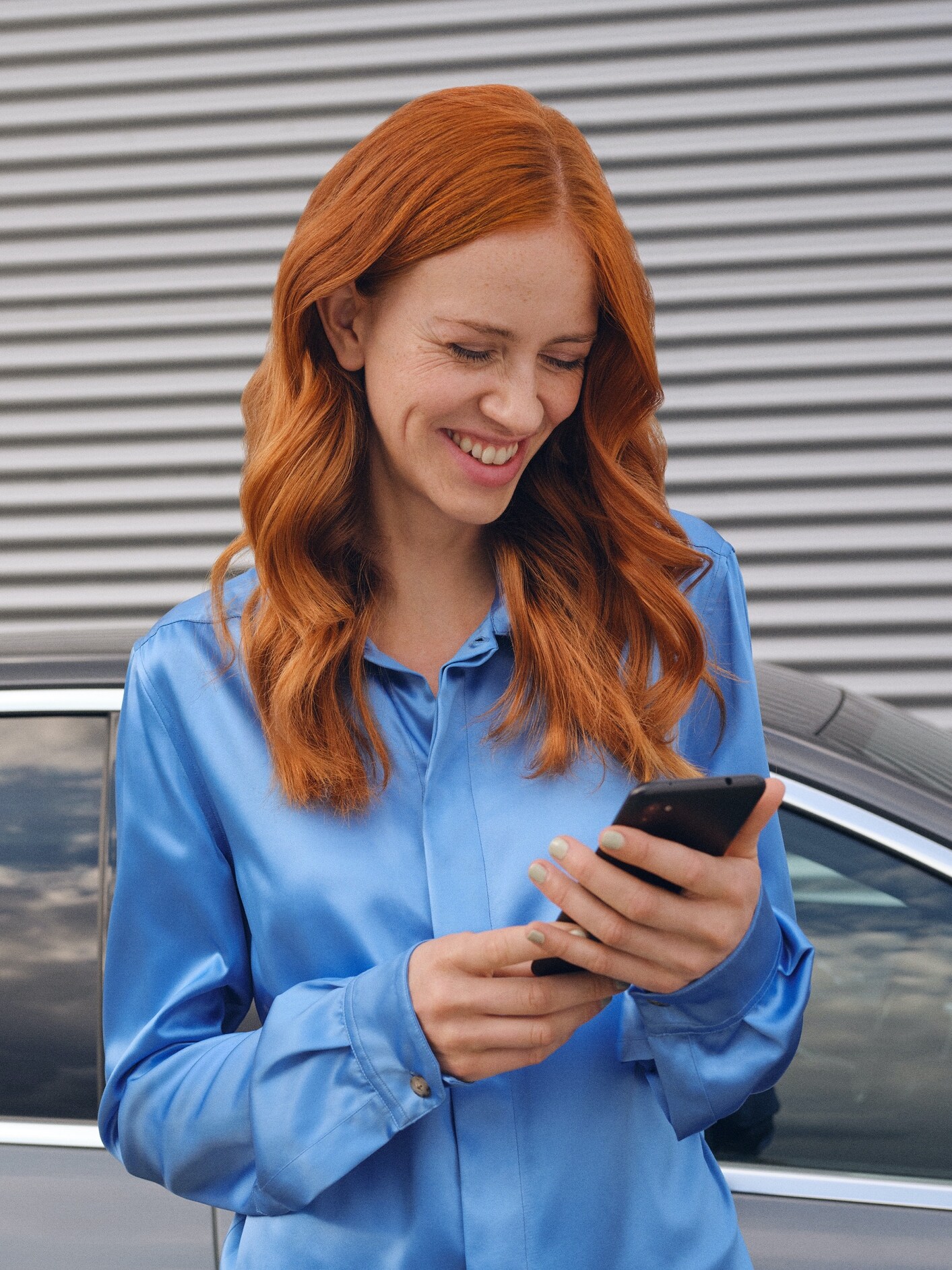 A woman connects to her Mercedes-Benz via the Mercedes-Benz App on her smartphone.