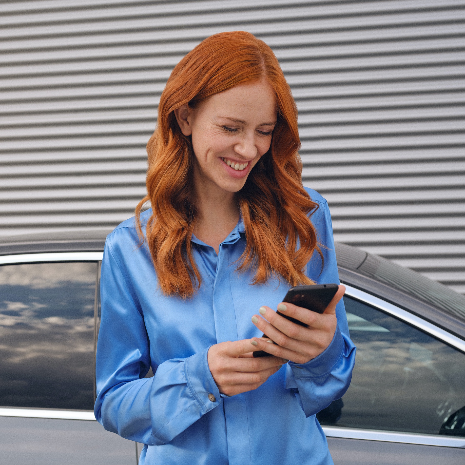 A woman connects to her Mercedes-Benz via the Mercedes-Benz App on her smartphone. A woman connects to her Mercedes-Benz via the Mercedes-Benz App on her smartphone.
