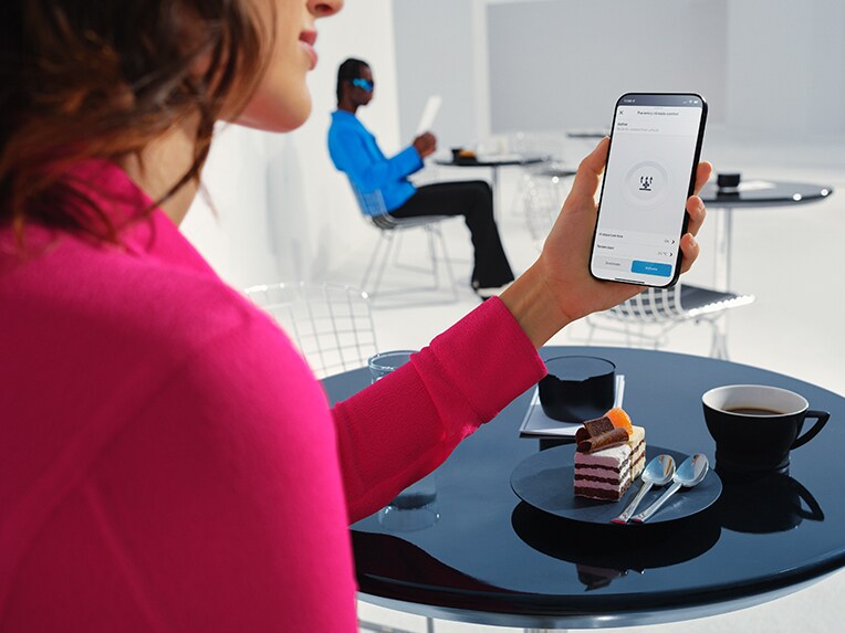Woman holding her cell phone in her hand and using the Mercedes me App.