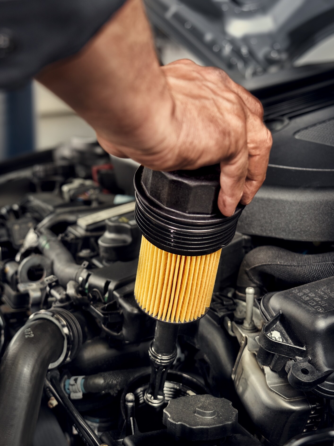 A Mercedes-Benz technician changes the oil filter in the vehicle.