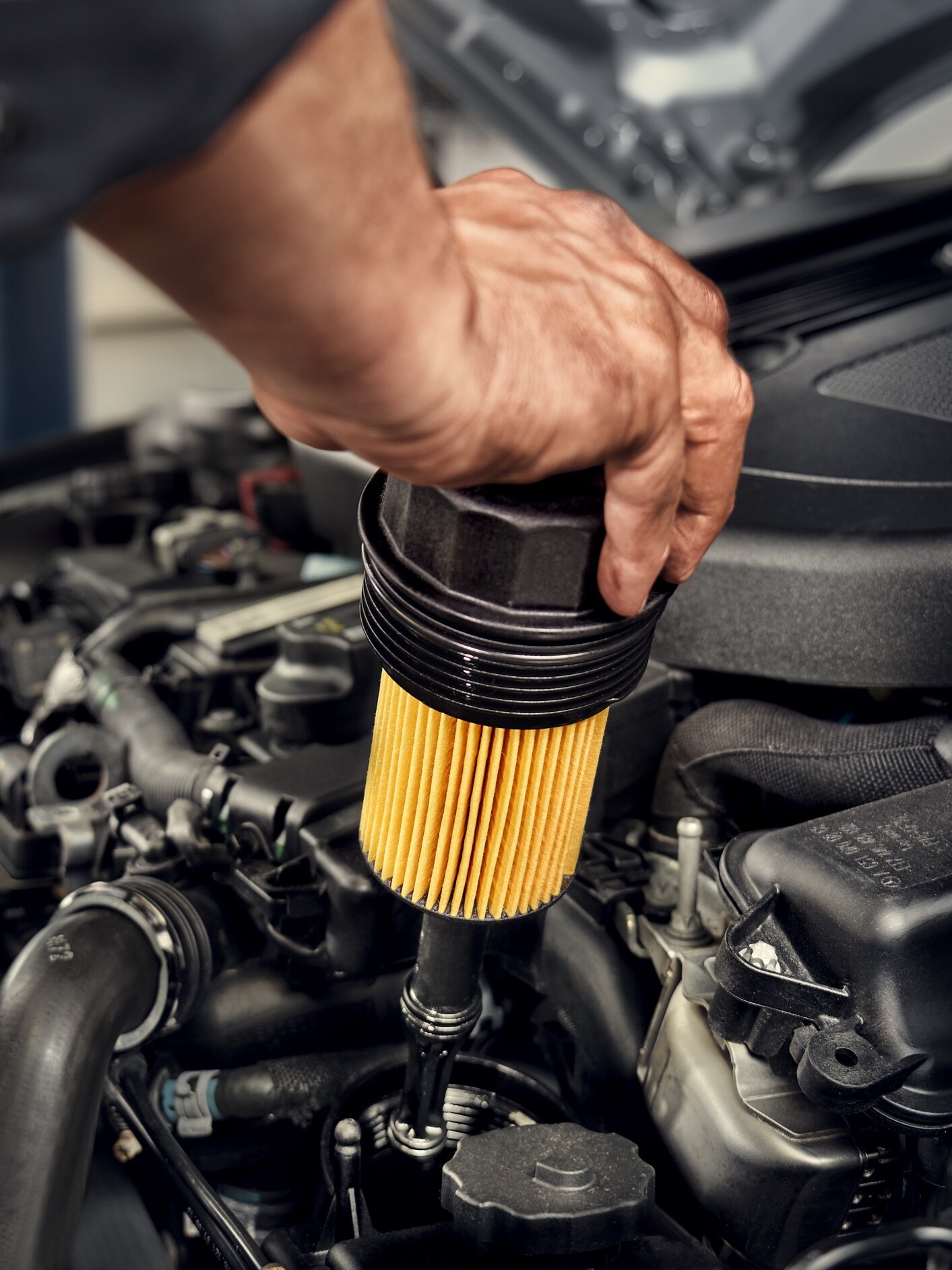A Mercedes-Benz technician changes the oil filter in the vehicle.