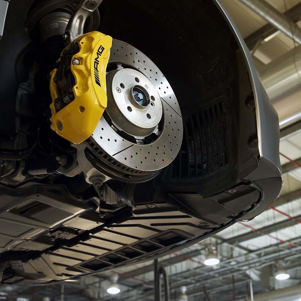 A Mercedes-Benz technician checks the underside of a vehicle.
