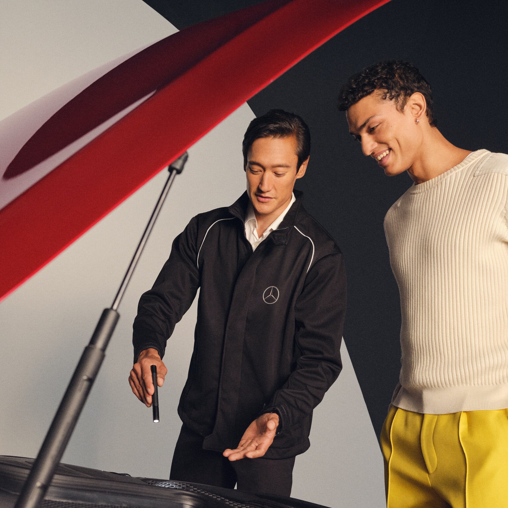 A Mercedes-Benz mechanic and a man stand in front of the open bonnet of a Mercedes-Benz.