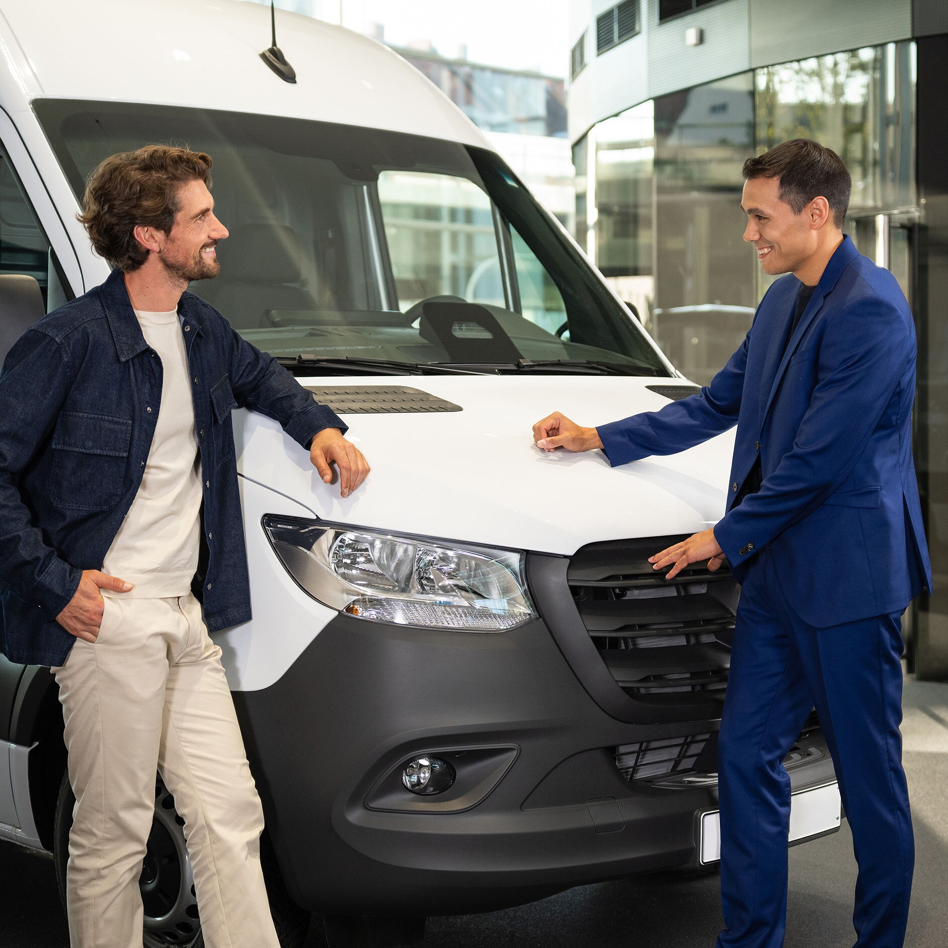 Two people standing in front of a Mercedes-Benz van.