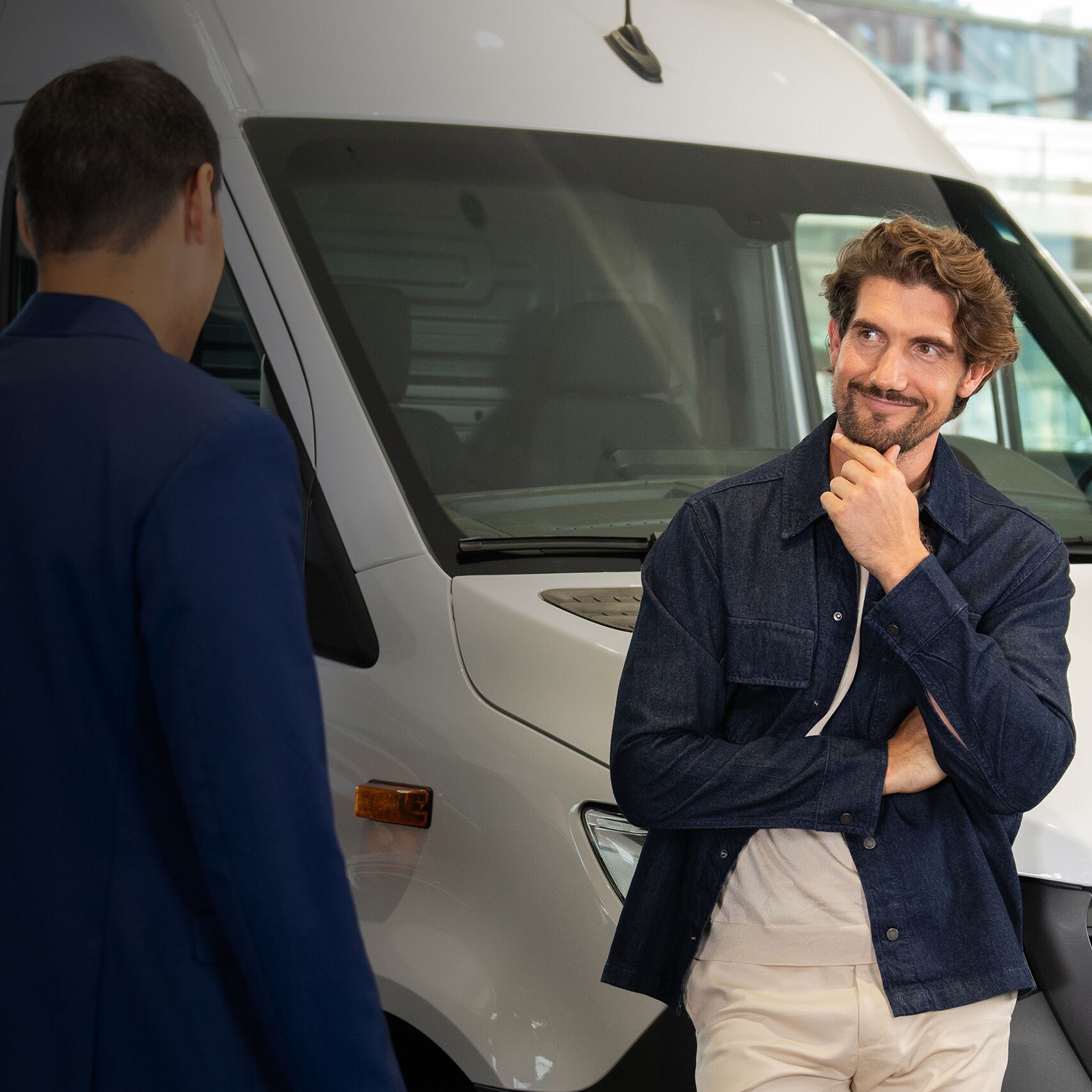Two people talking in front of a Mercedes-Benz van.
