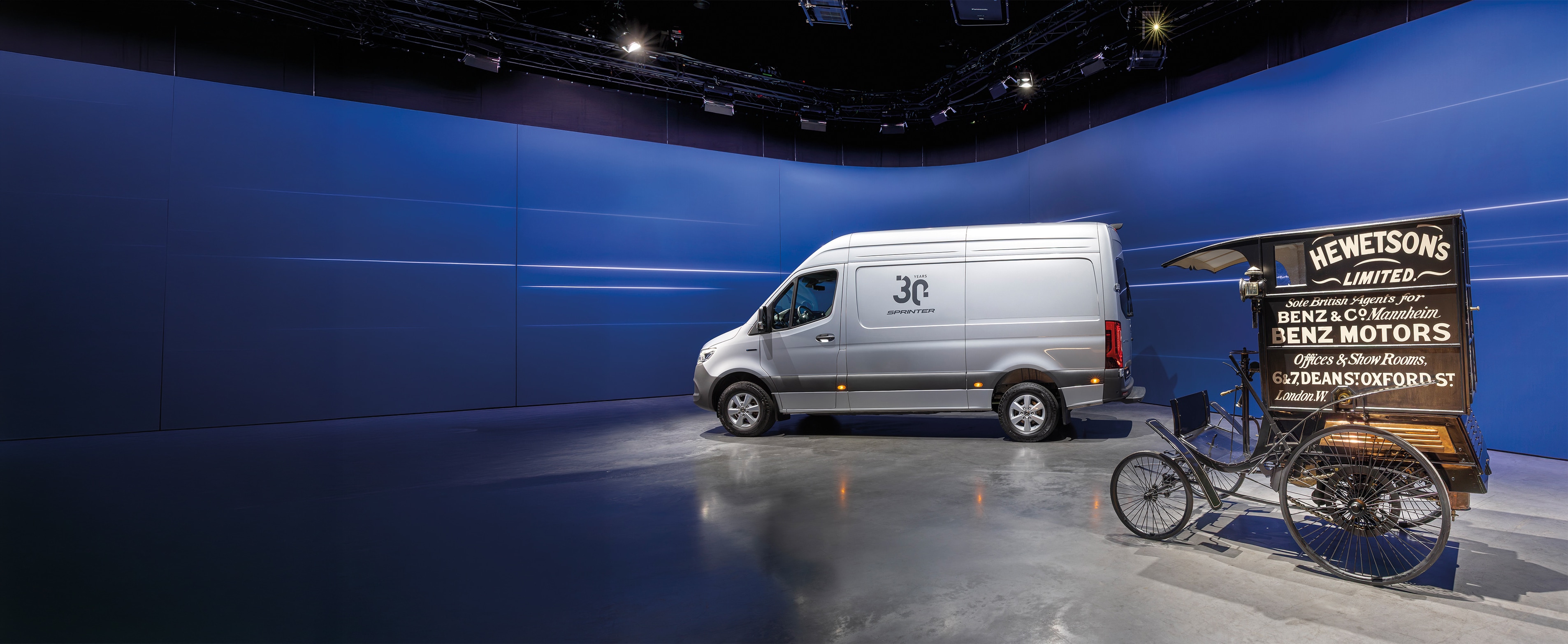 History | Commercial vehicles | Mercedes-Benz Mercedes-Benz Sprinter van and historic Benz delivery vehicle displayed in modern showroom
