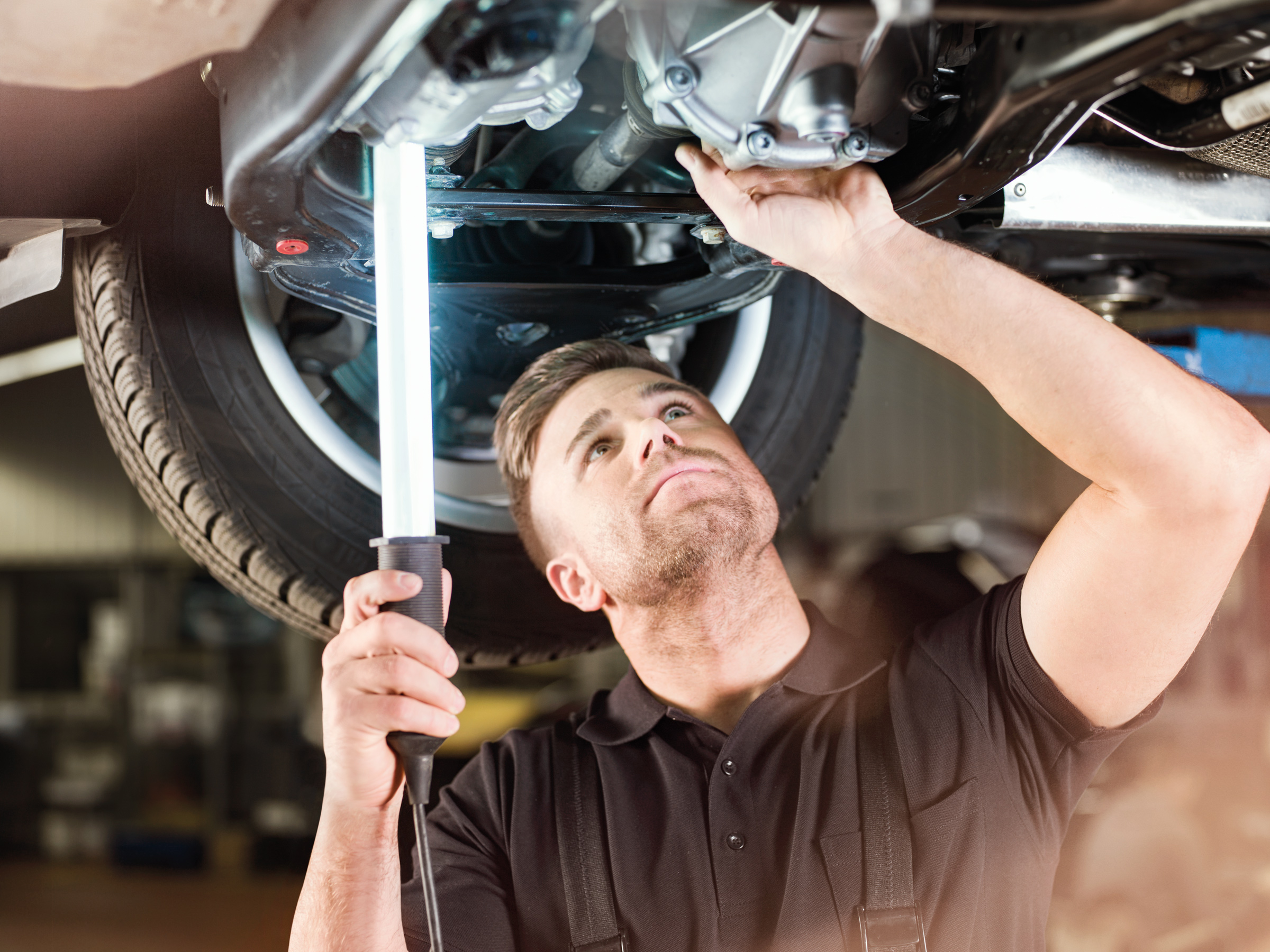 Mercedes-Benz | Services Overview | Electric Van Services Three employees standing in front of a silver Mercedes-Benz eSprinter with charging cable attached.