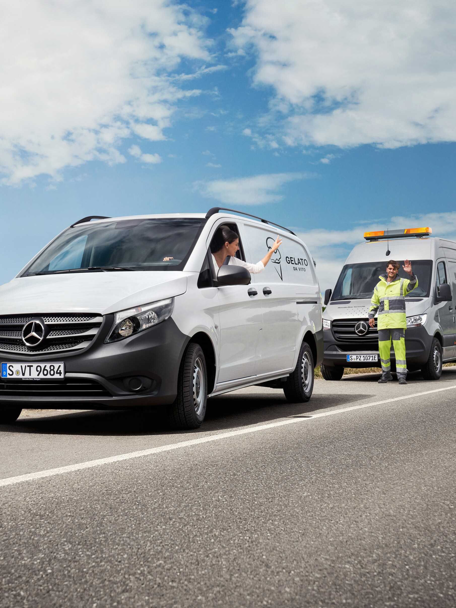 A woman seated in a white Mercedes-Benz Vito waves at a Mercedes-Benz servicing technician at the side of the road.