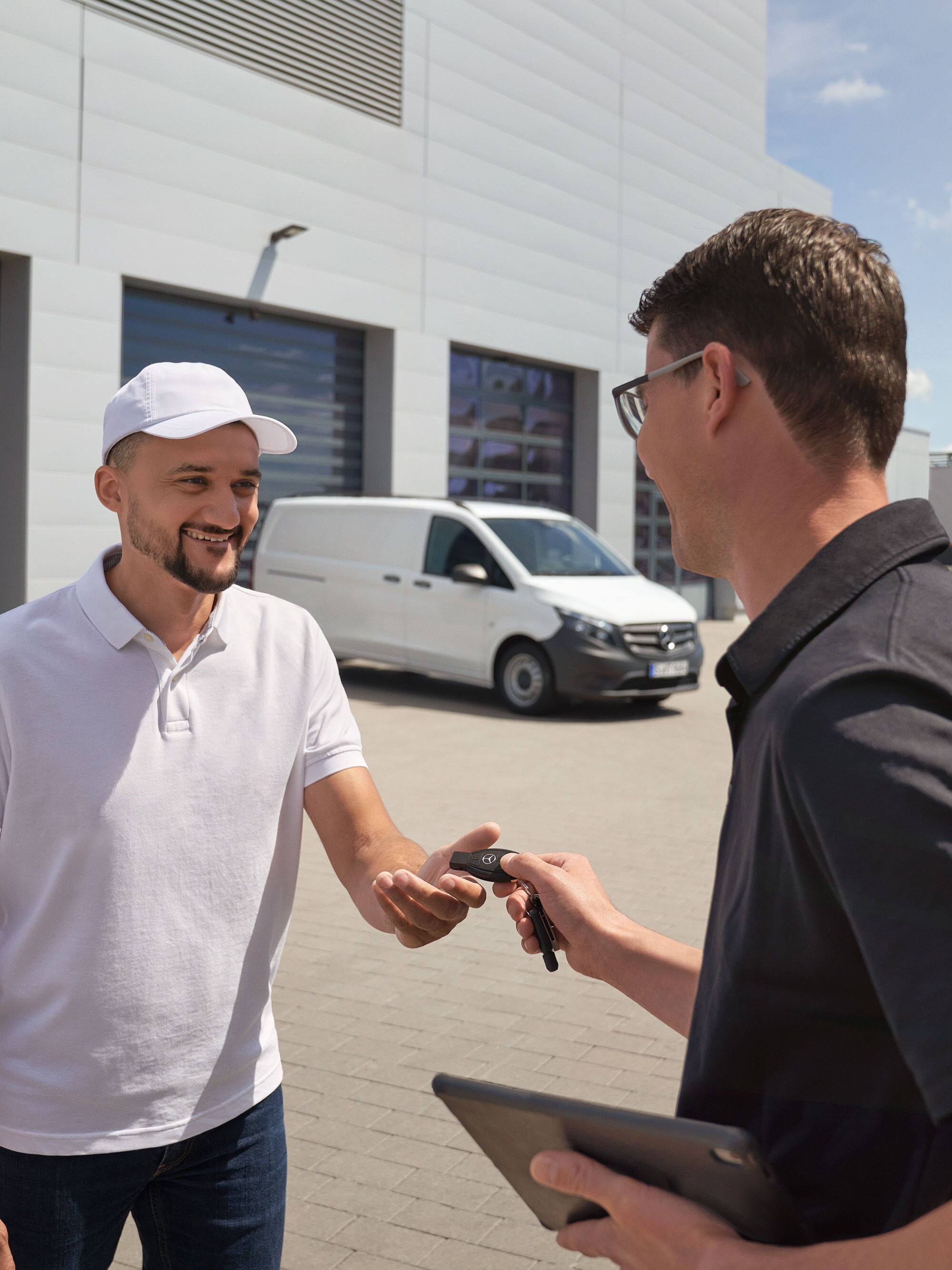Mercedes-Benz technican handing over keys to a customer with a white Mercedes-Benz Vito van in the background.