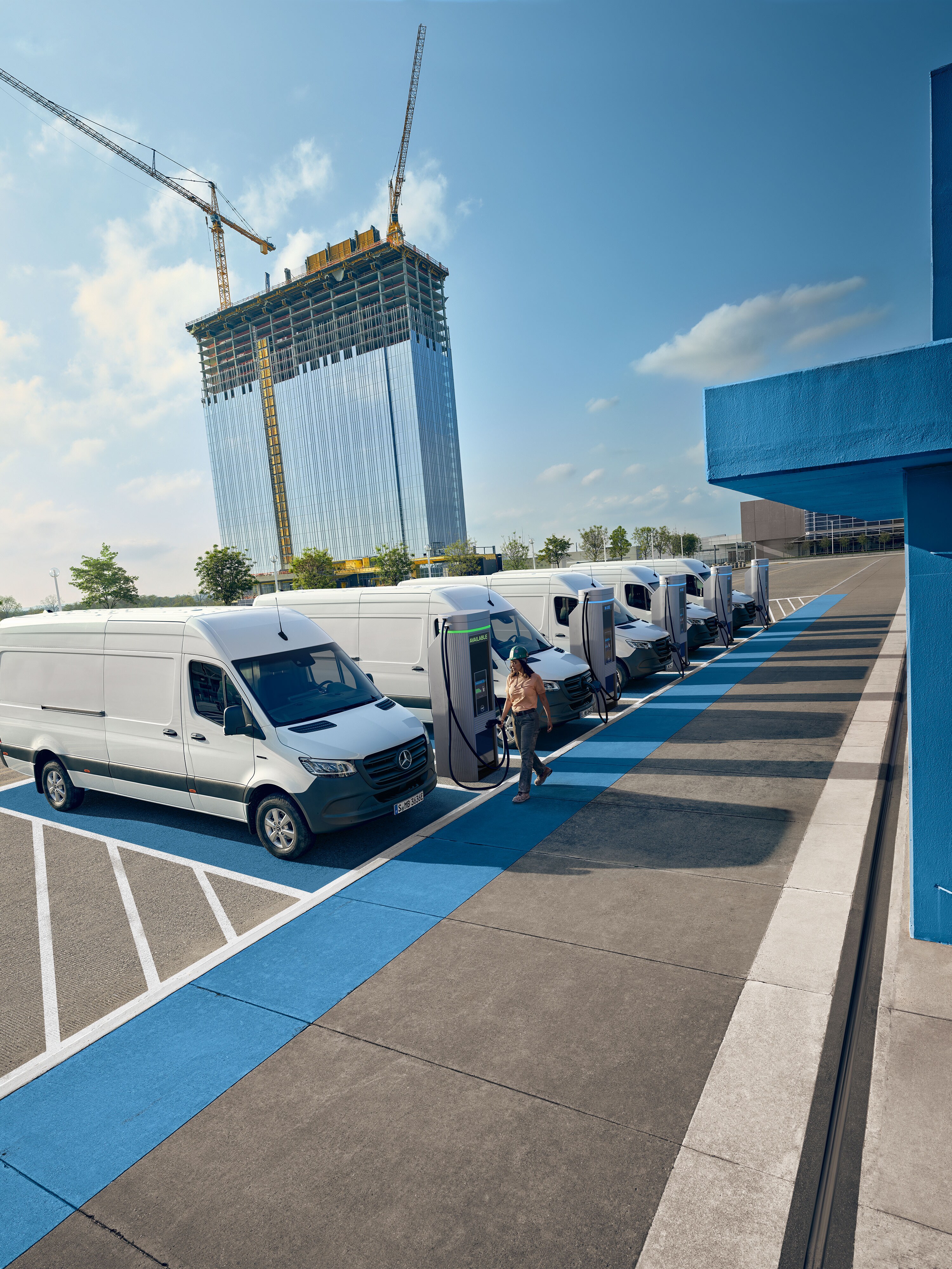 A fleet of white electric Mercedes-Benz vans parked at a charging hub station.