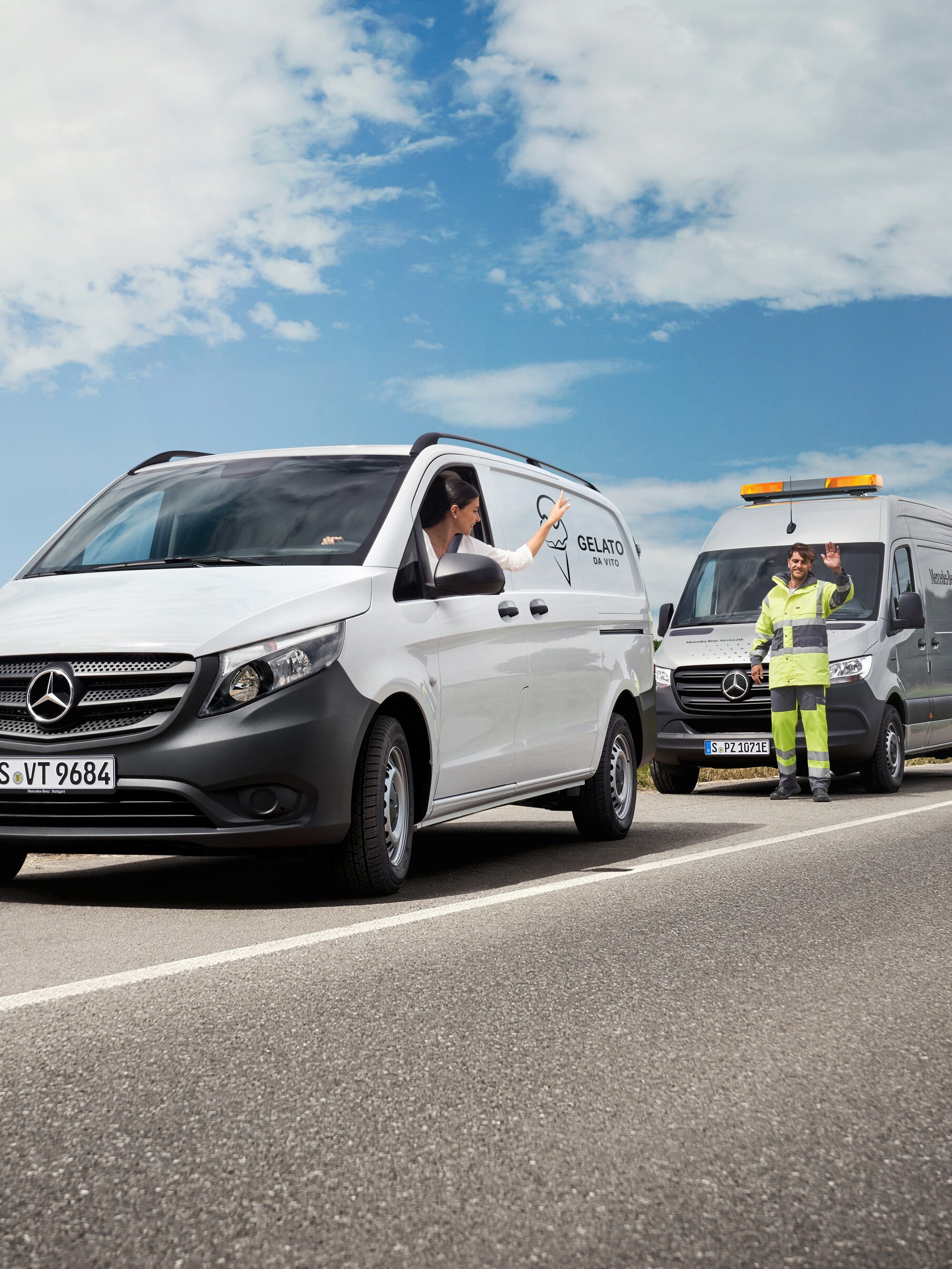 A woman seated in a white Mercedes-Benz Vito waves at a Mercedes-Benz servicing technician at the side of the road. 