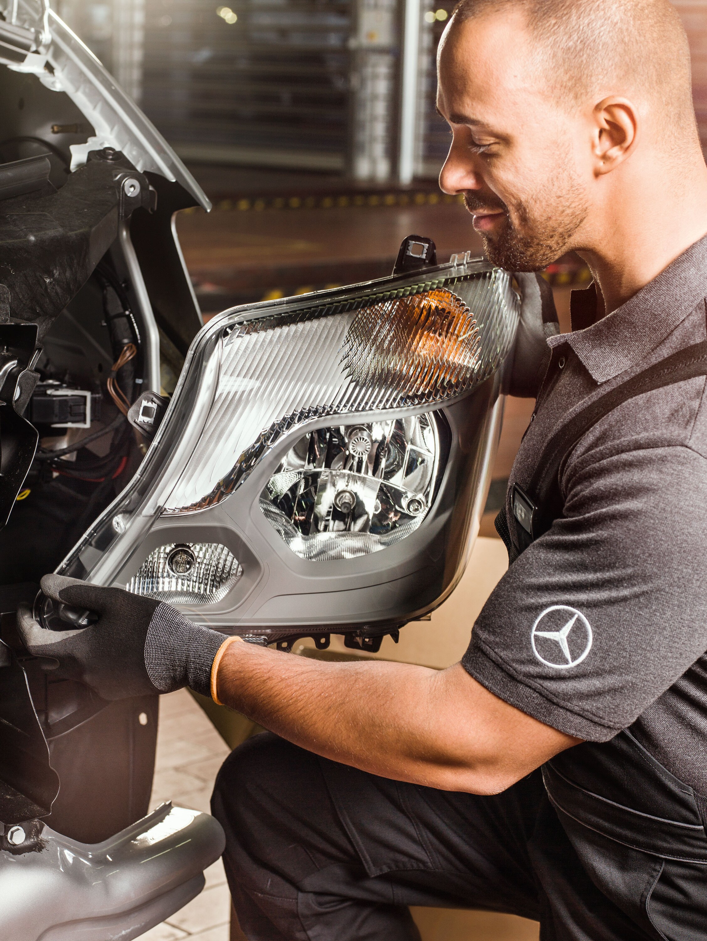 Mechanic checking Mercedes-Benz Genuine Parts in front of an open Sprinter engine, matching the Mercedes spare parts catalogue. 