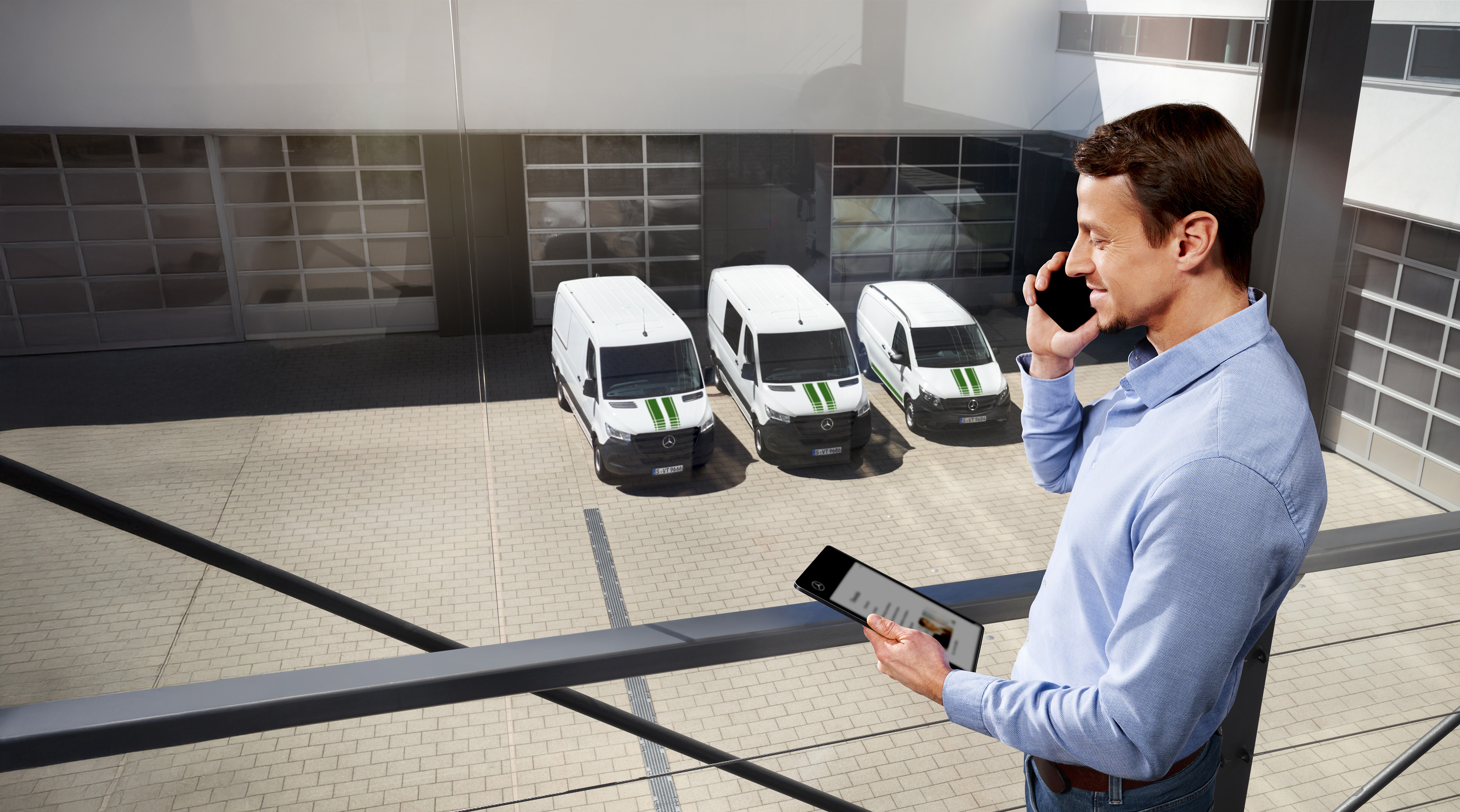 Mercedes-Benz | Vans Quality Warranty Man on the phone with tablet in front of three Mercedes-Benz vans, topic: how long is the manufacturer’s warranty at Mercedes-Benz?