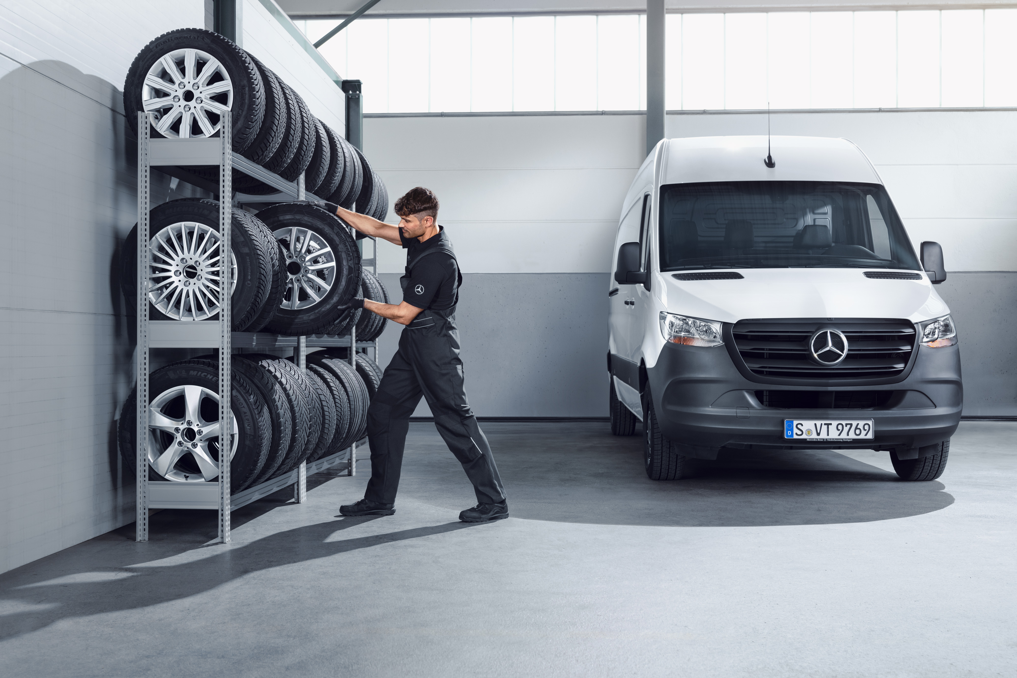Mercedes-Benz | Vans Quality GenuineParts Mechanic selecting Mercedes-Benz complete winter wheels for a white Sprinter from the workshop shelf.