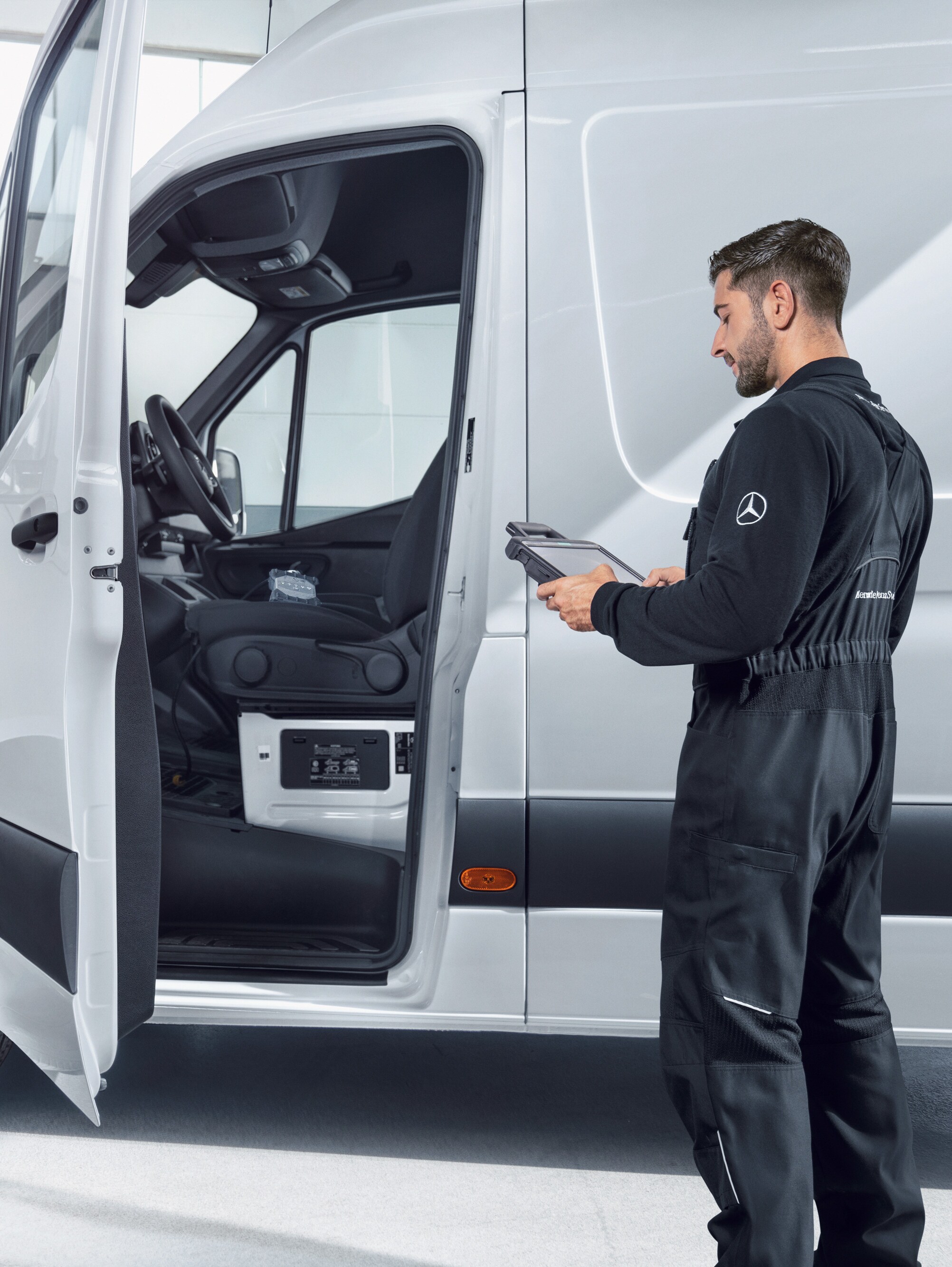 Mechanic checking a white Mercedes-Benz van with a tablet, symbolising quality standards and the quality promise.