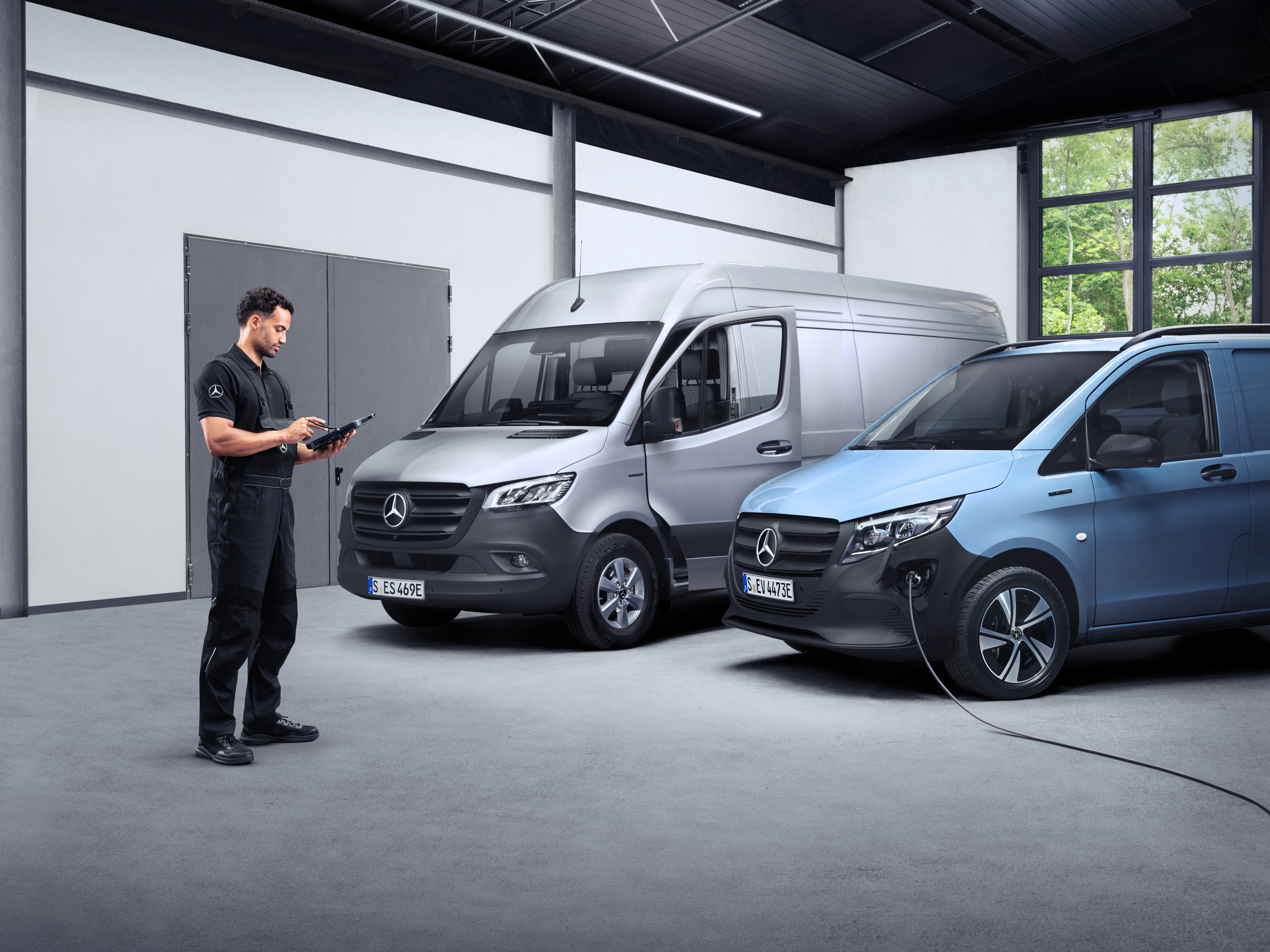 Mercedes-Benz | Van ServiceCare A technician infront of two eVans on a tablet