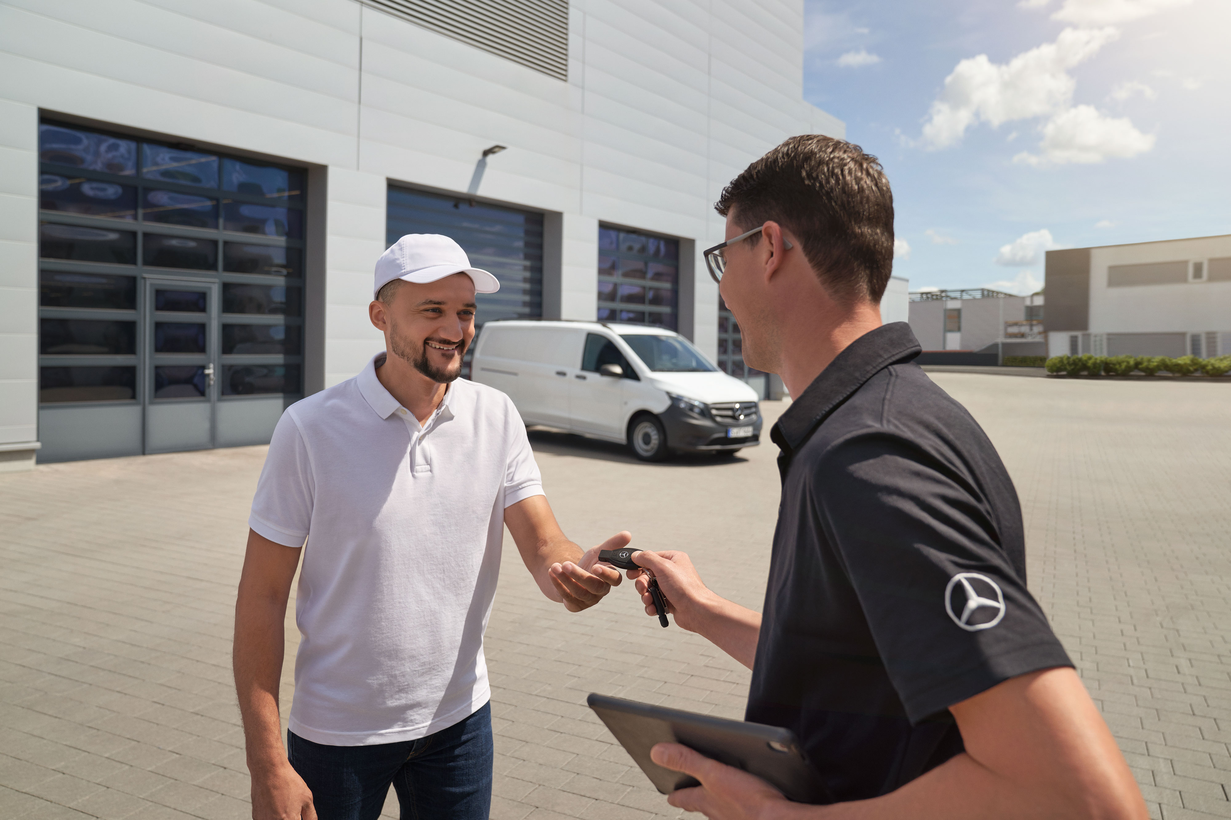 Mercedes-Benz | Van ServiceCare | Additional options A technician handing over key fob to a customer with a white Mercedes-Benz Vito van in the background.