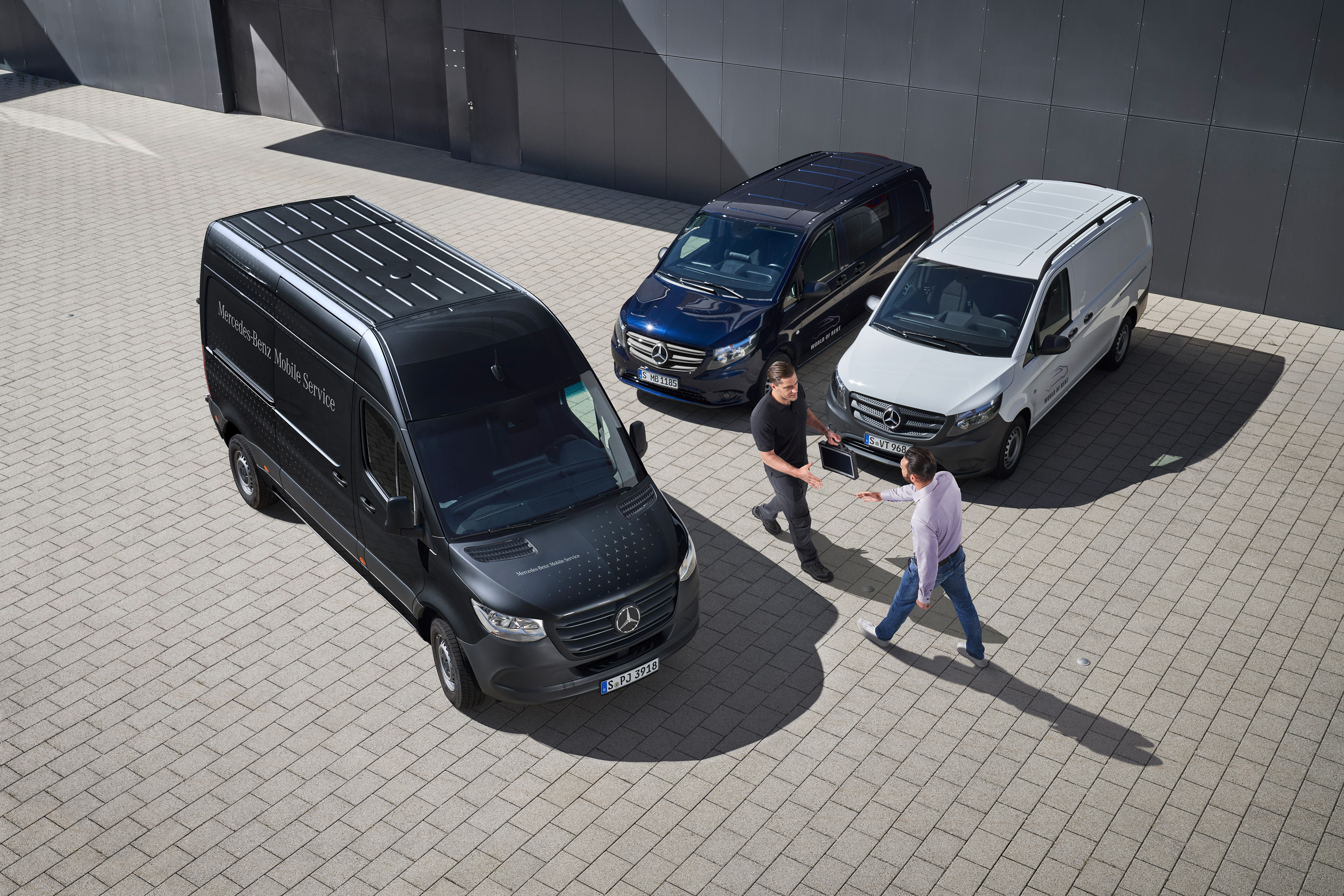 Mercedes-Benz | Services Overview | Mobile Service Two men greet each other amongst Mercedes-Benz vans.