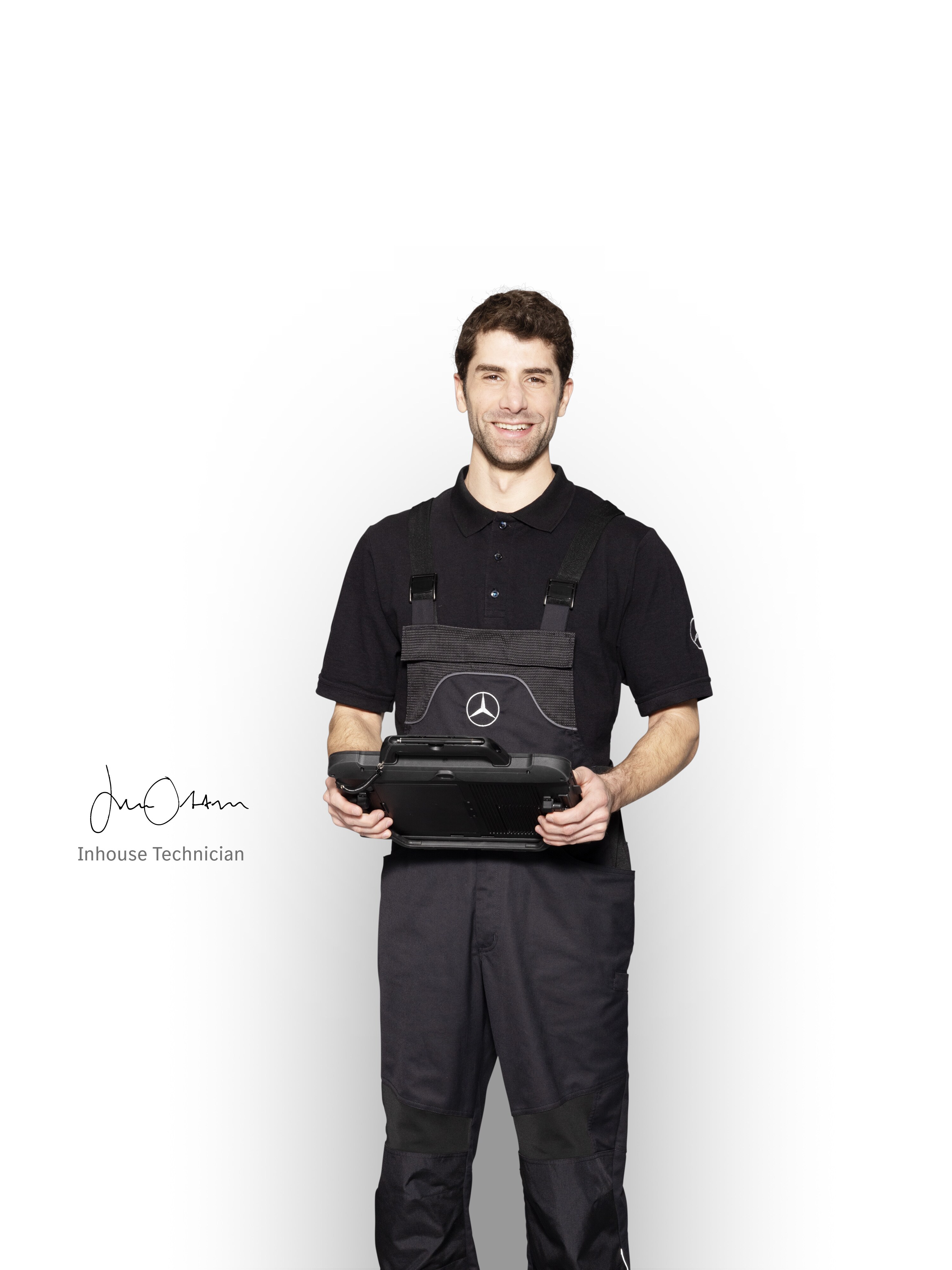 Mercedes-Benz mechanic in work clothes holding a tablet ready for damage reporting.
