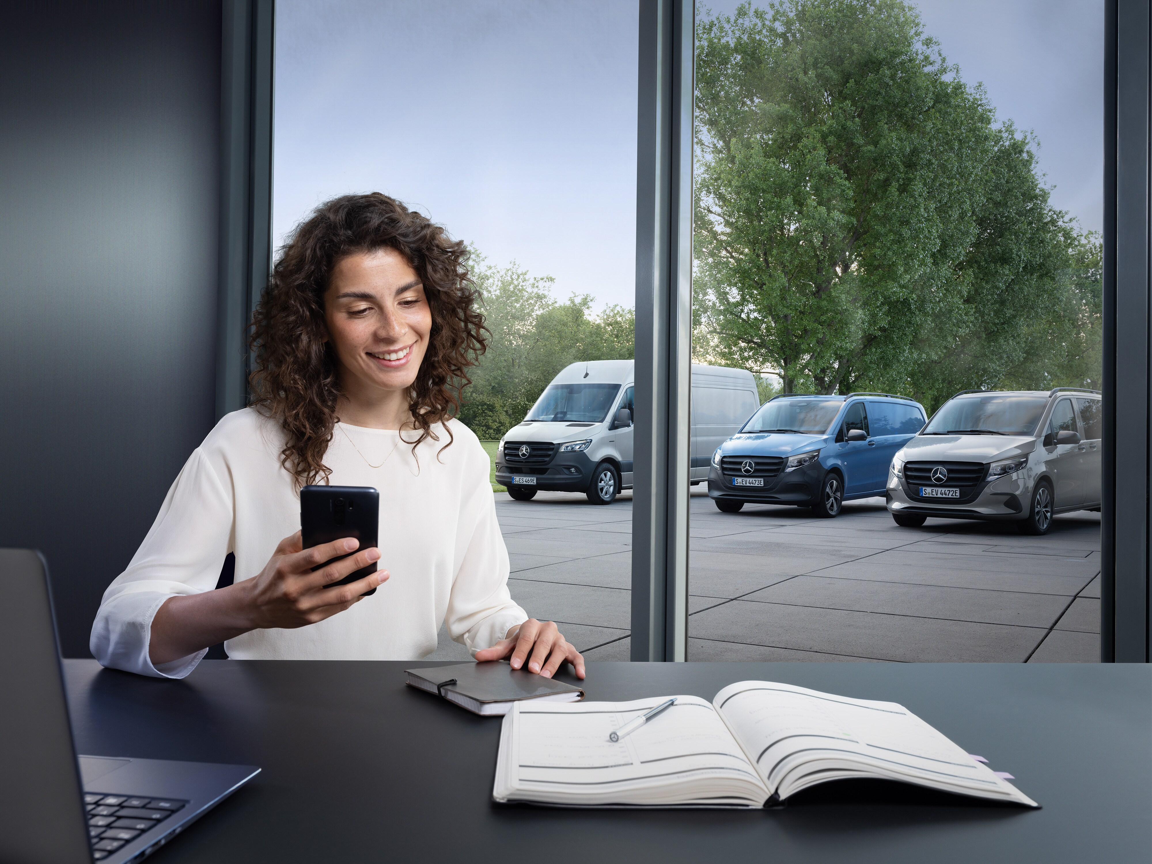 Woman planning on her smartphone in front of Mercedes-Benz vans