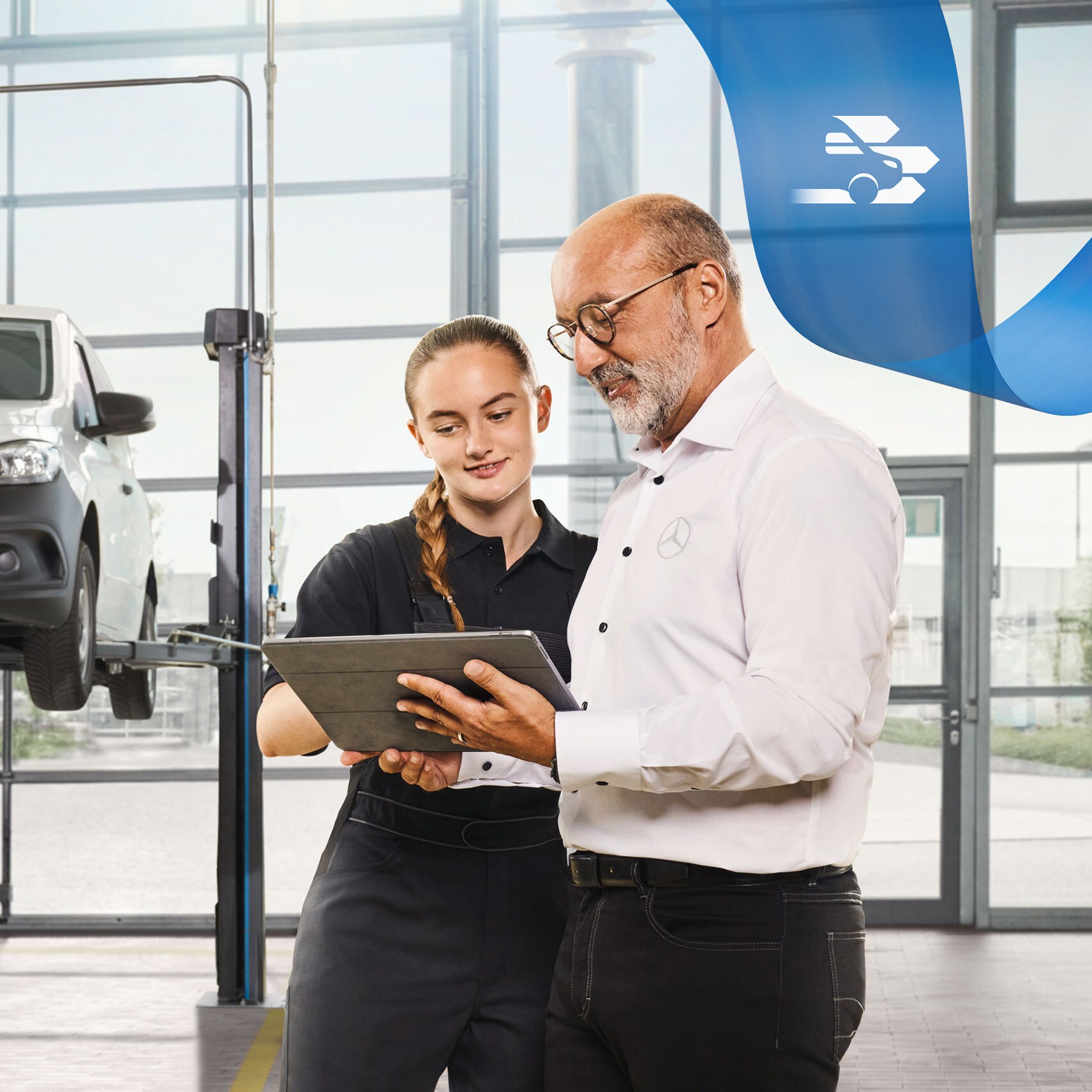 Two employees discuss the commercial vehicle service on a jacked-up Mercedes-Benz van in the workshop.