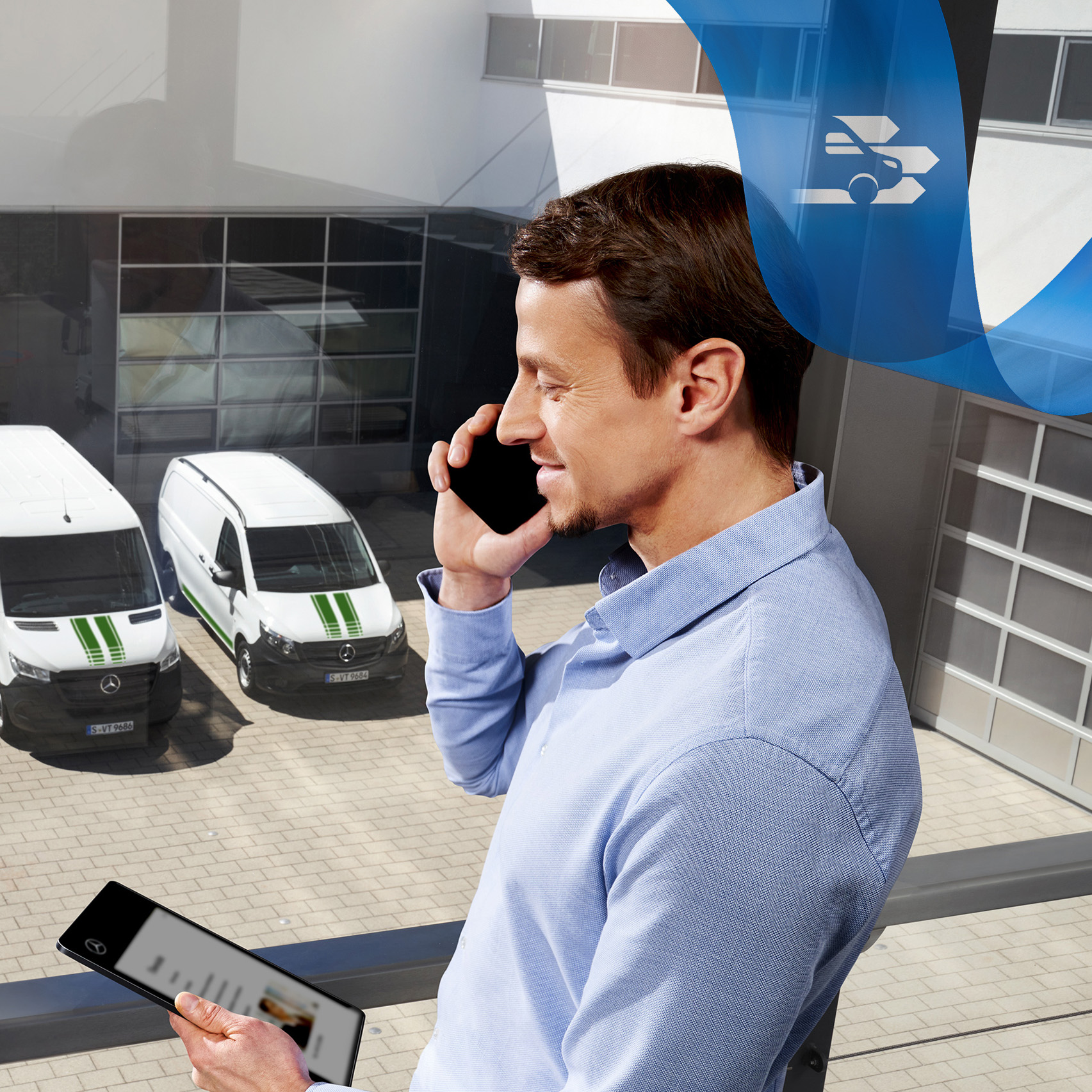 Mercedes-Benz | Vans Fleet Services A man talking on the phone, while looking at a tablet, with a range of Mercedes-Benz vans in the background.