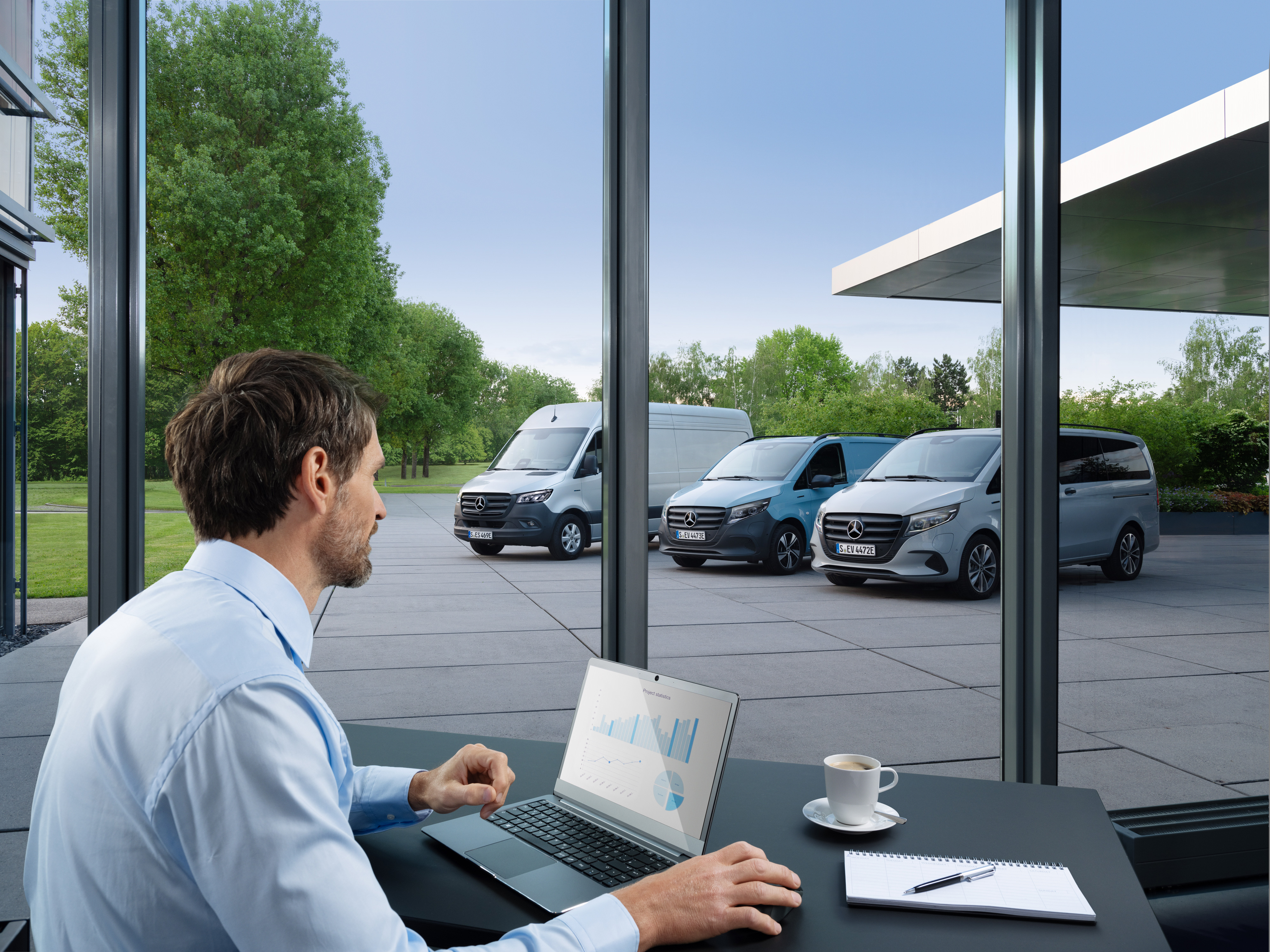 Mercedes-Benz | Van technology | Van Uptime Monitor Man monitoring several parked Mercedes-Benz vans with a laptop, symbol of digital fleet management.