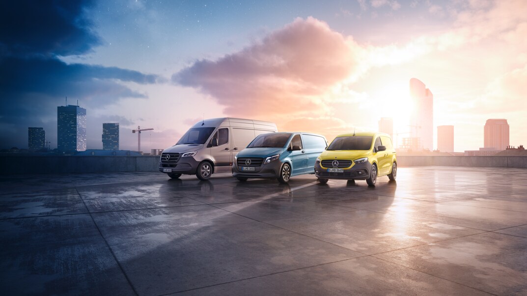 Three Mercedes-Benz panel vans – a grey Sprinter, a blue Vito, and a yellow Citan – positioned on a rooftop with a cityscape backdrop.