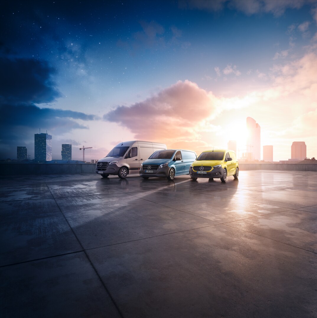 Three Mercedes-Benz panel vans – a grey Sprinter, a blue Vito, and a yellow Citan – positioned on a rooftop with a cityscape backdrop.