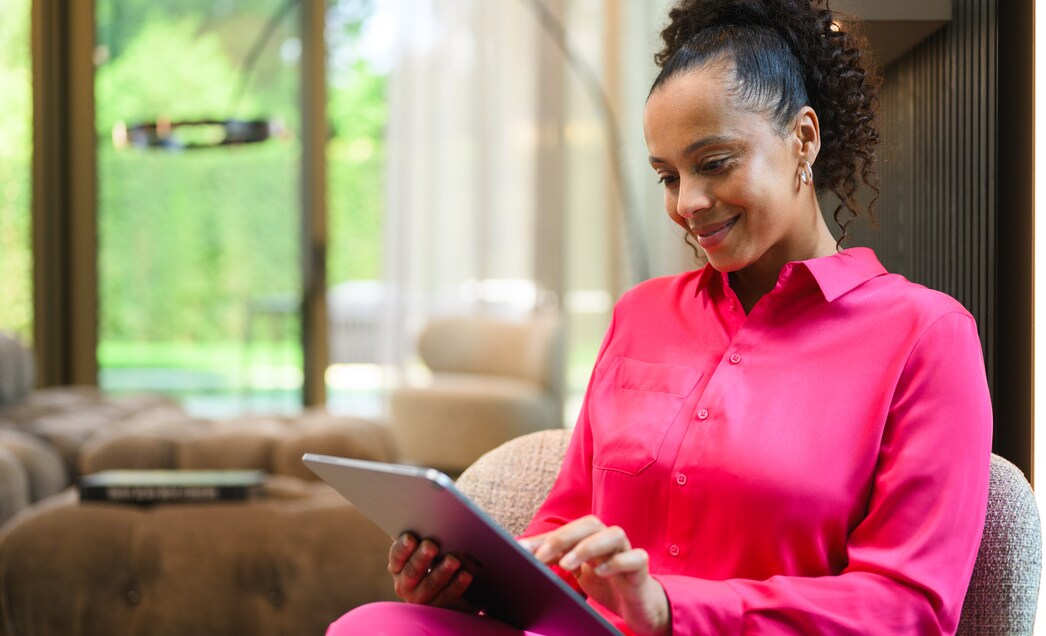 A person at home looking at a tablet device and smiling.