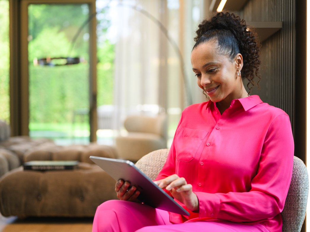 Mercedes-Benz Finance Portal A person at home looking at a tablet device and smiling.