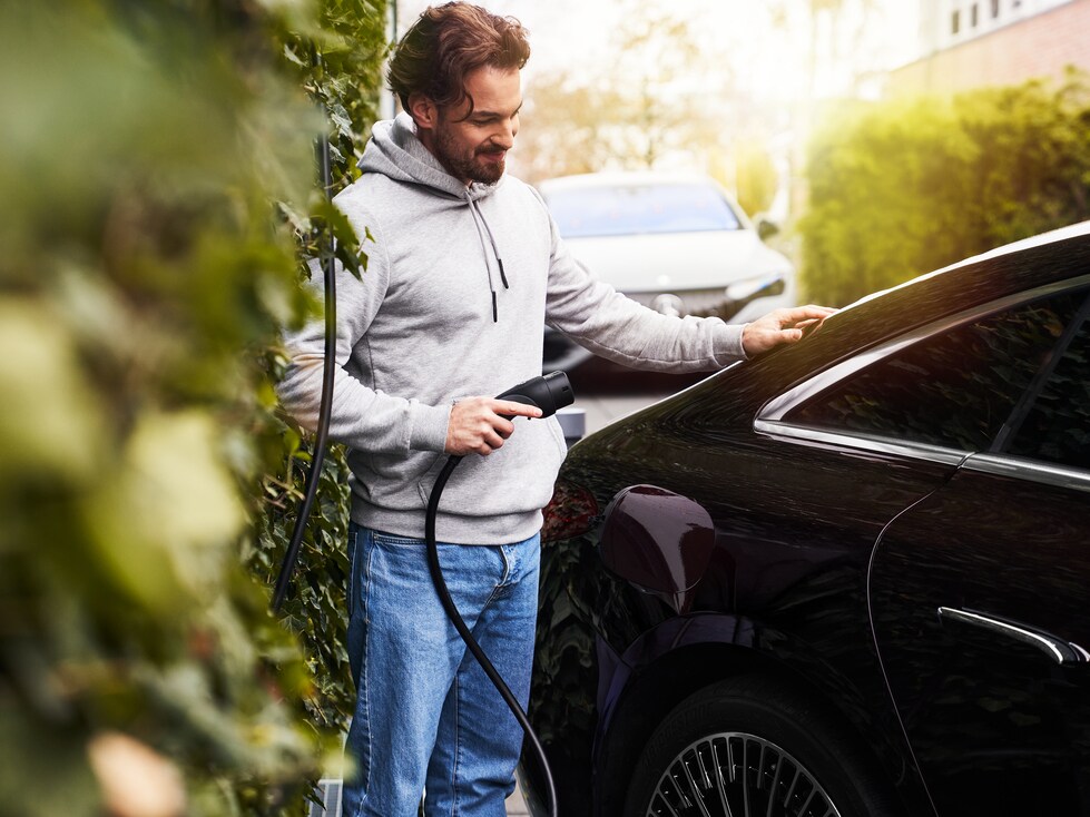 A man conveniently charges their Mercedes-Benz at a charging station using Charging Digital Extras .