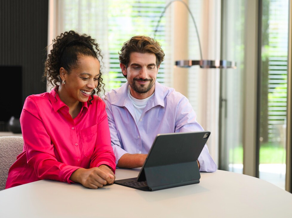 Two people seated at a table using a laptop indoors 