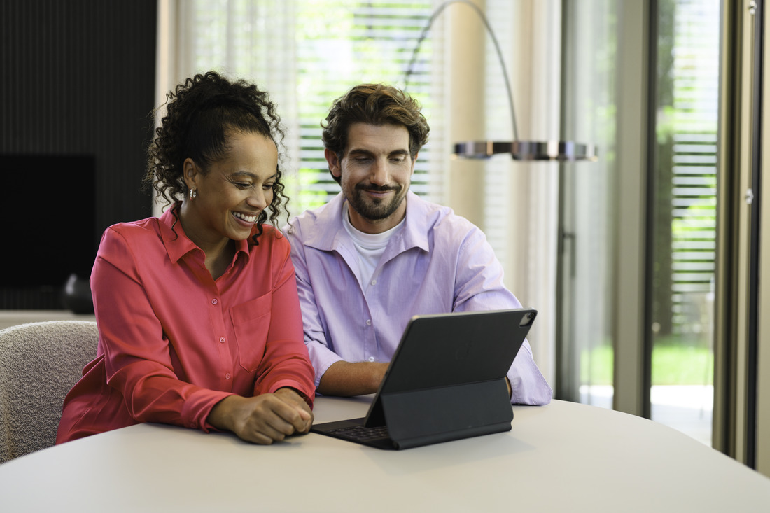 Two people seated at a table using a laptop indoors Two people seated at a table using a laptop indoors