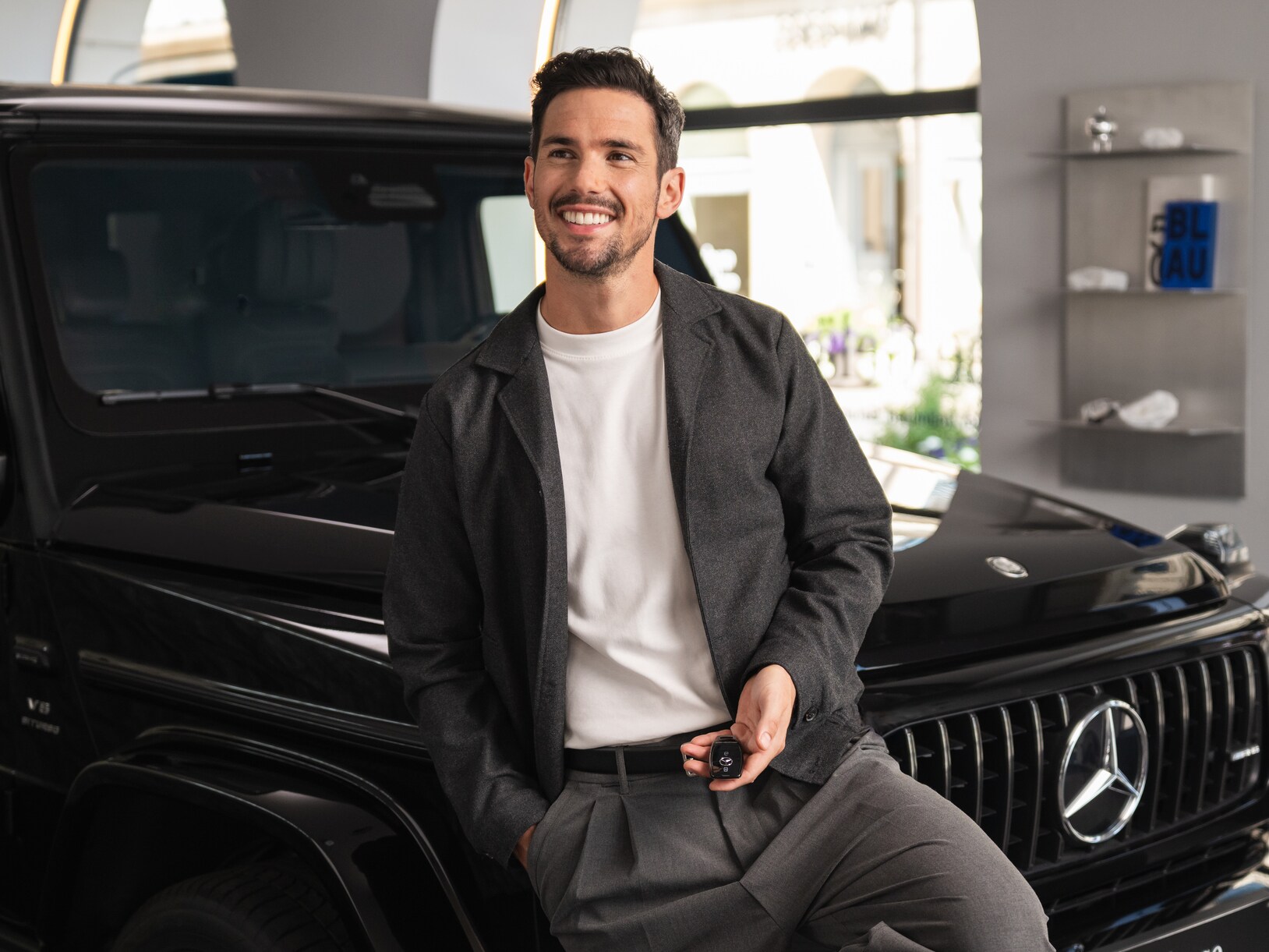 A person smiling in front of a Mercedes-Benz.