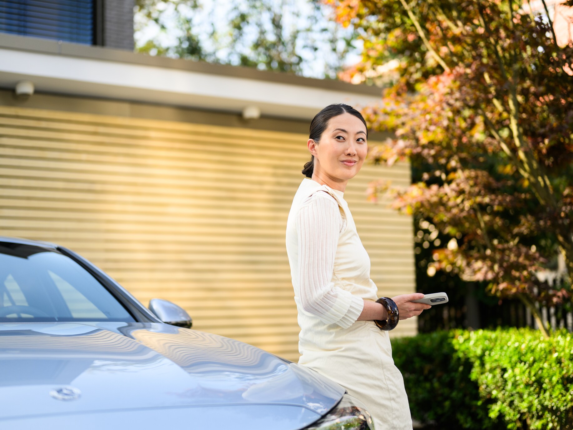 A person leaning against a Mercedes-Benz outside their house.