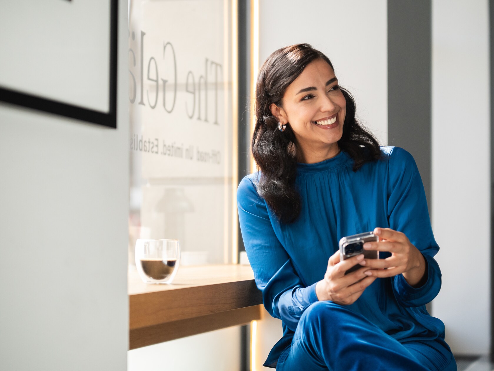 A person smiling and looking at her phone.