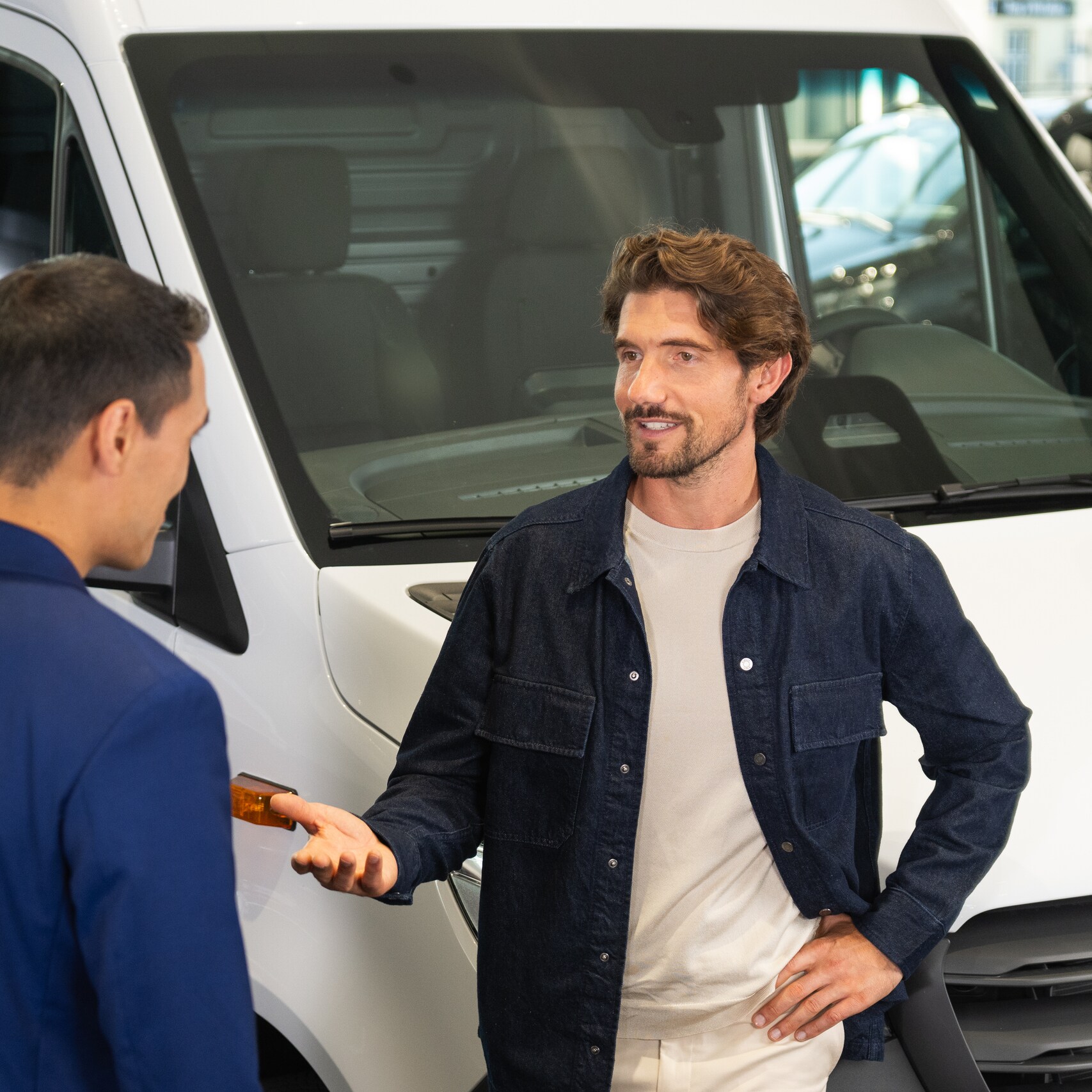 Two people talking to each other in front of a Mercedes-Benz van.