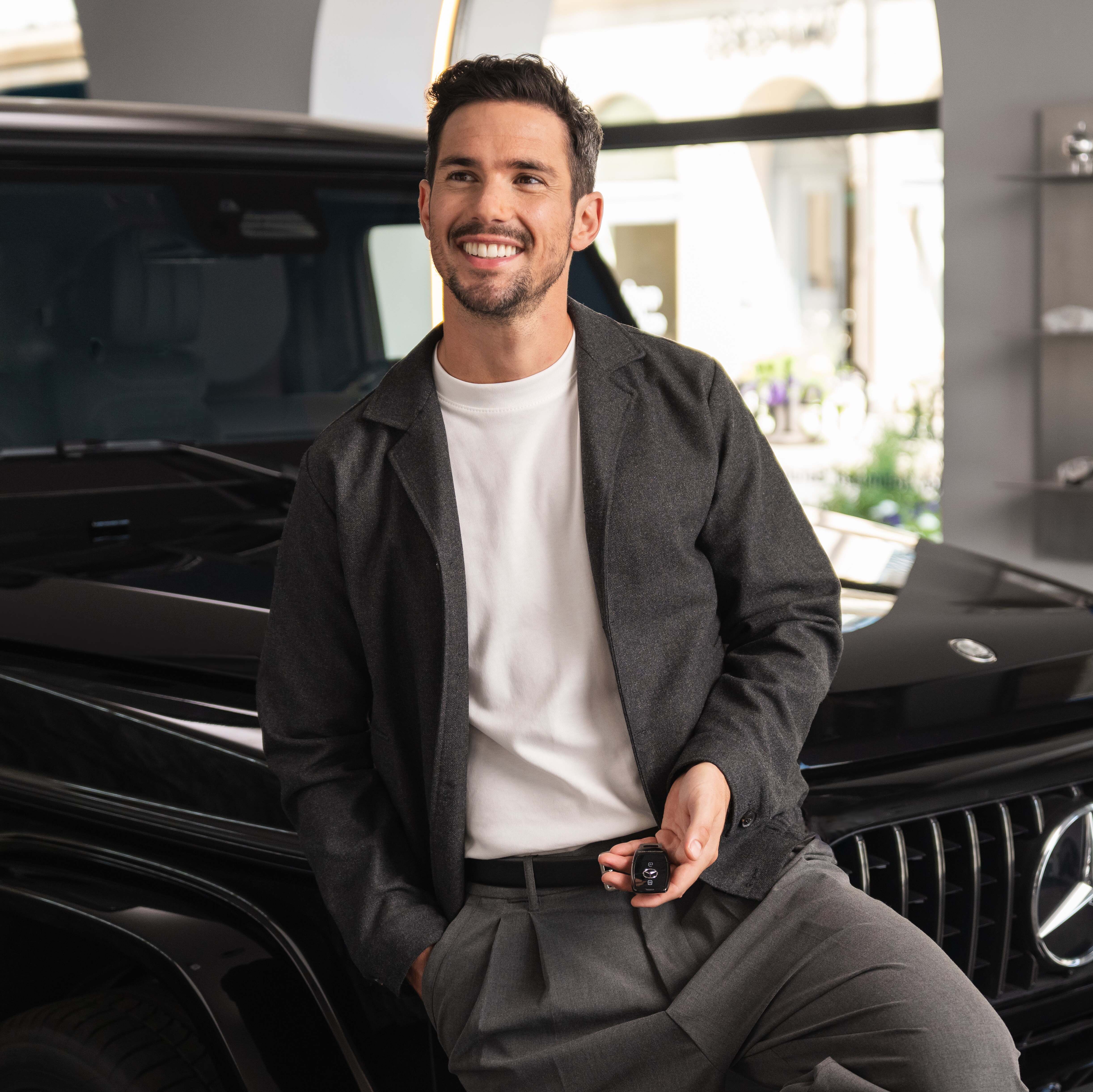 A person smiling in front of a Mercedes-Benz.
