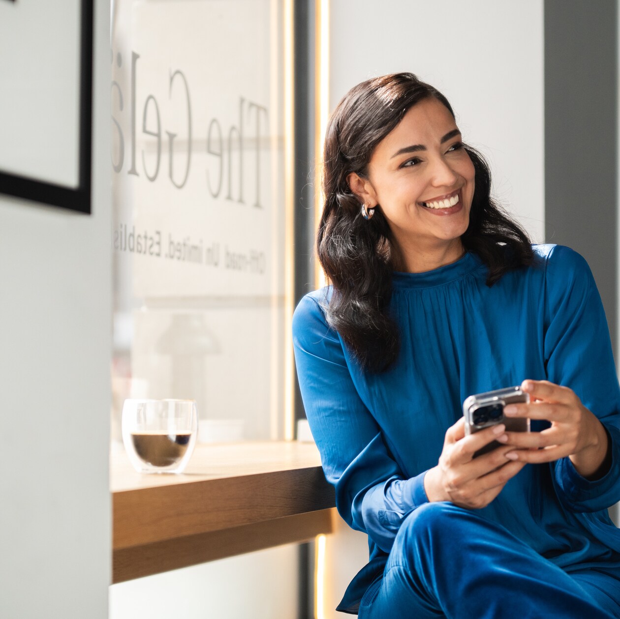 A person smiling and looking at her phone.