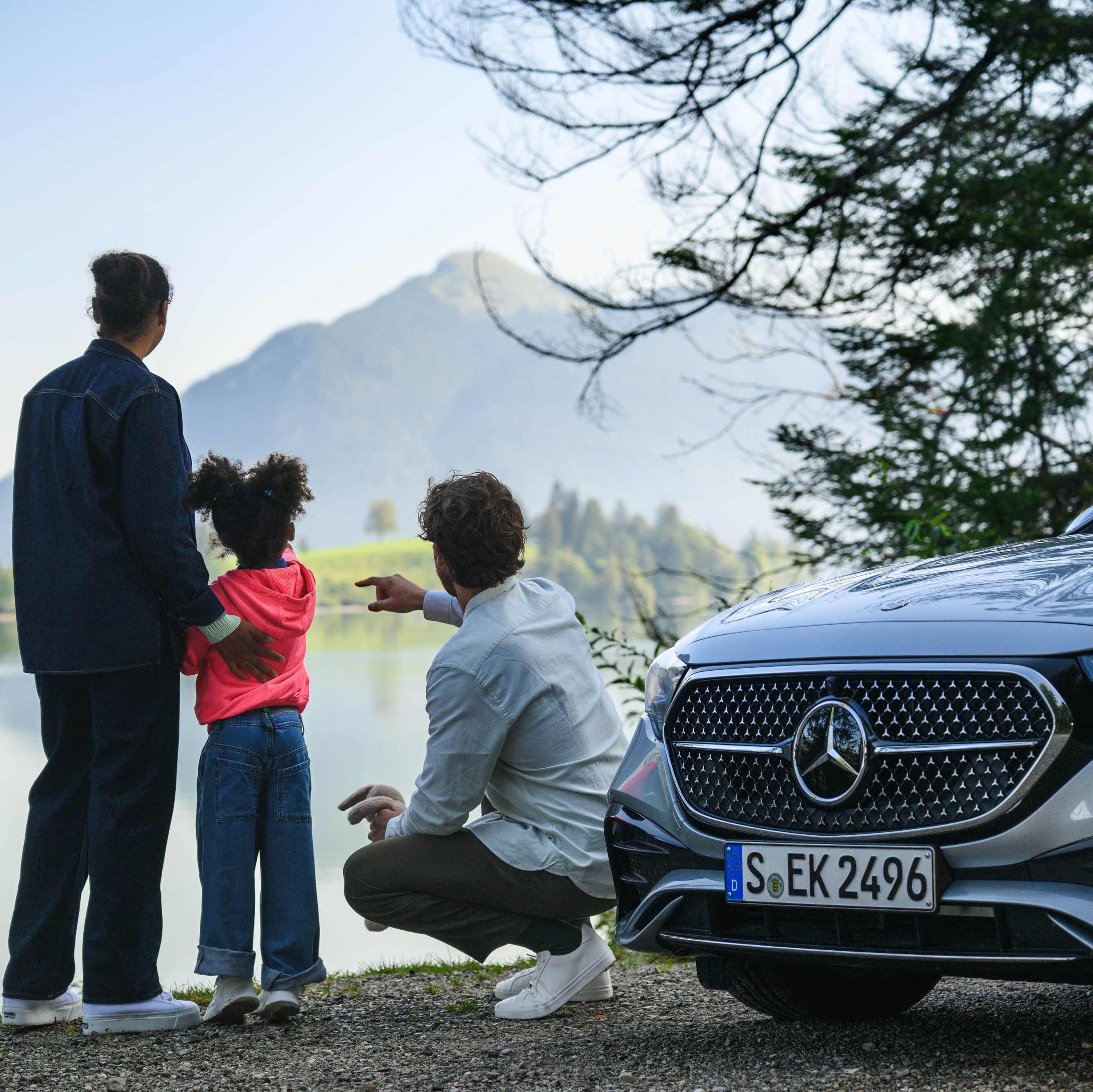 A family looking across a lake next to a Mercedes-Benz.​